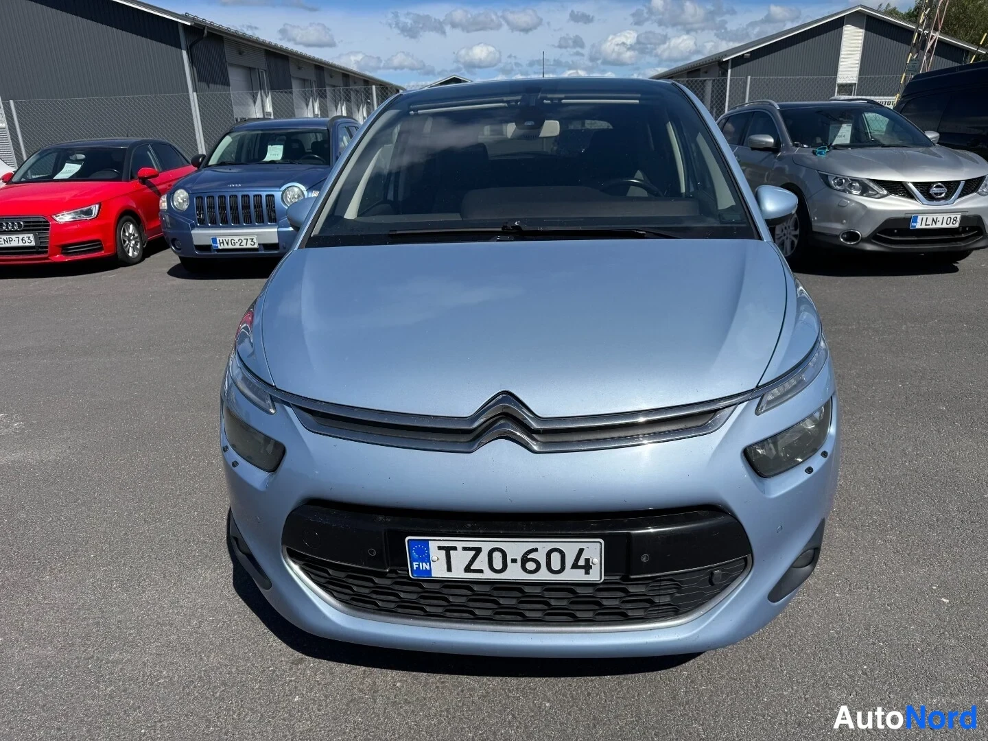 Edestä: Vaaleansinisen Citroen C4 Picasso:n etunäkymä suoraan edestä, rekisteritunnus TZ0-604.