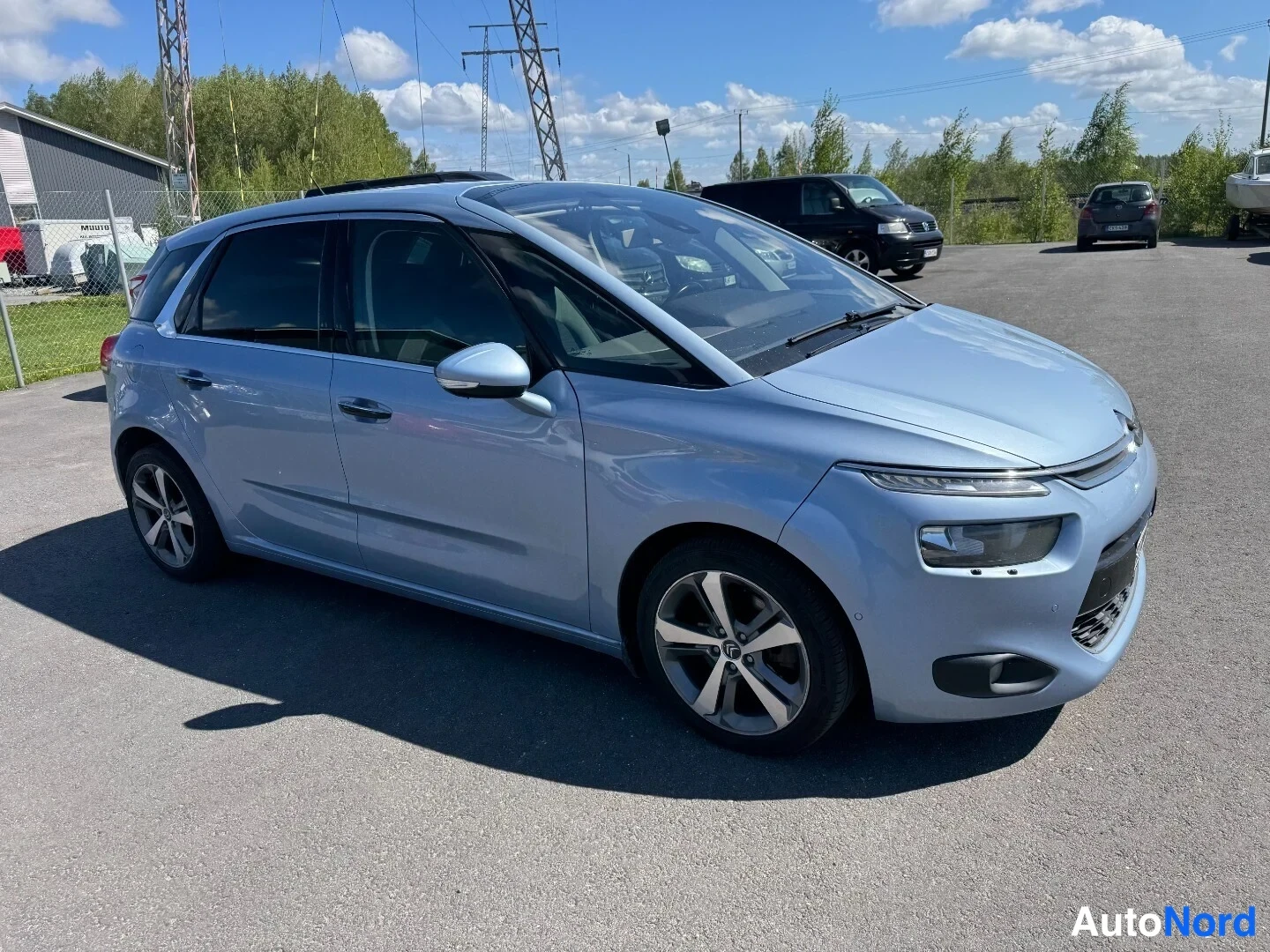 Etuviisto, nokka oikealle: Vaaleansininen Citroen C4 Picasso kolmannelta etukulmalta, nokka oikealla.