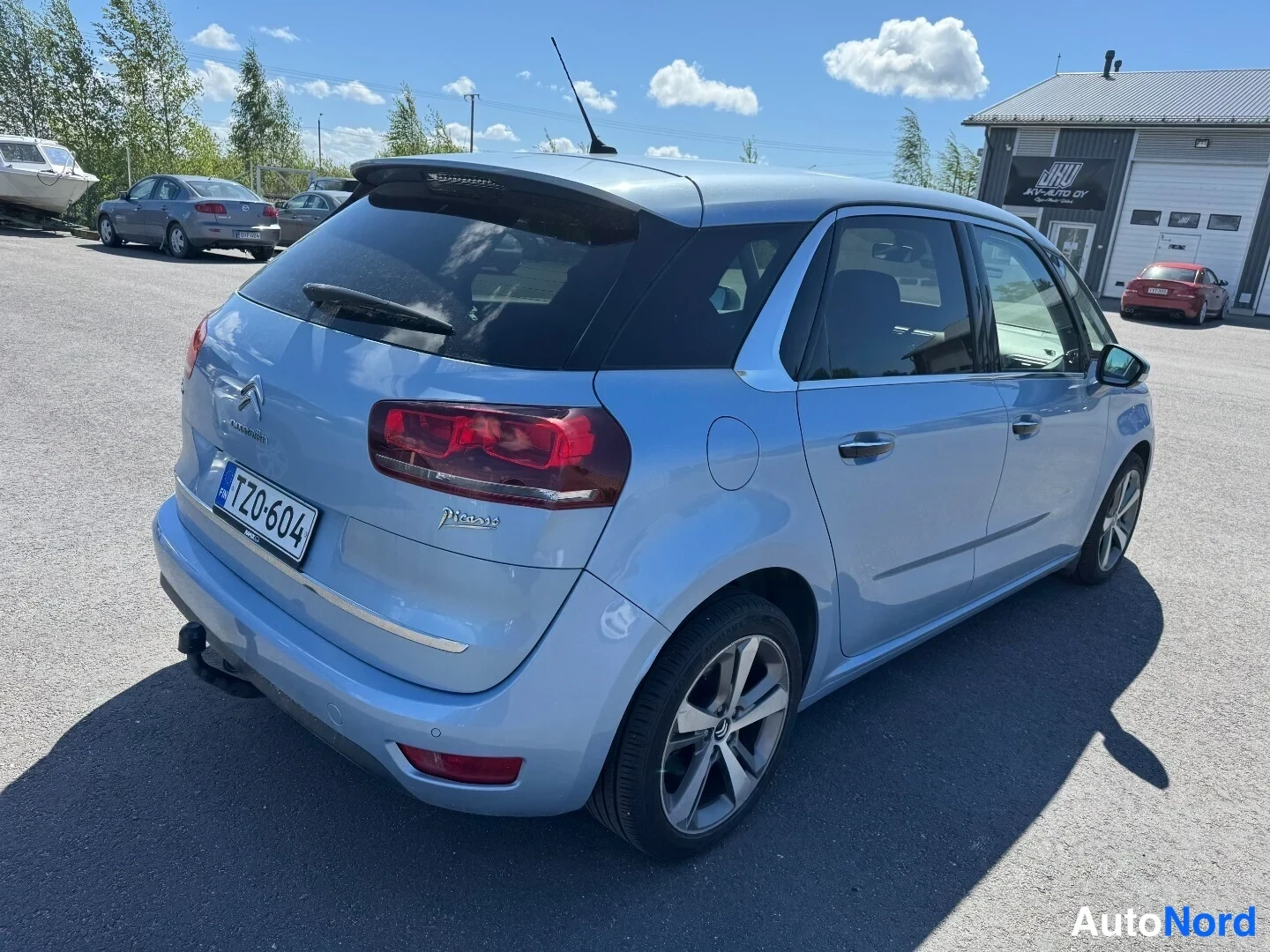 Takaviisto: Vaaleansininen Citroen C4 Picasso takaviistosta kuvattuna, rekisterikilpi TZ0-604 ja vetokoukku takapuskurissa.