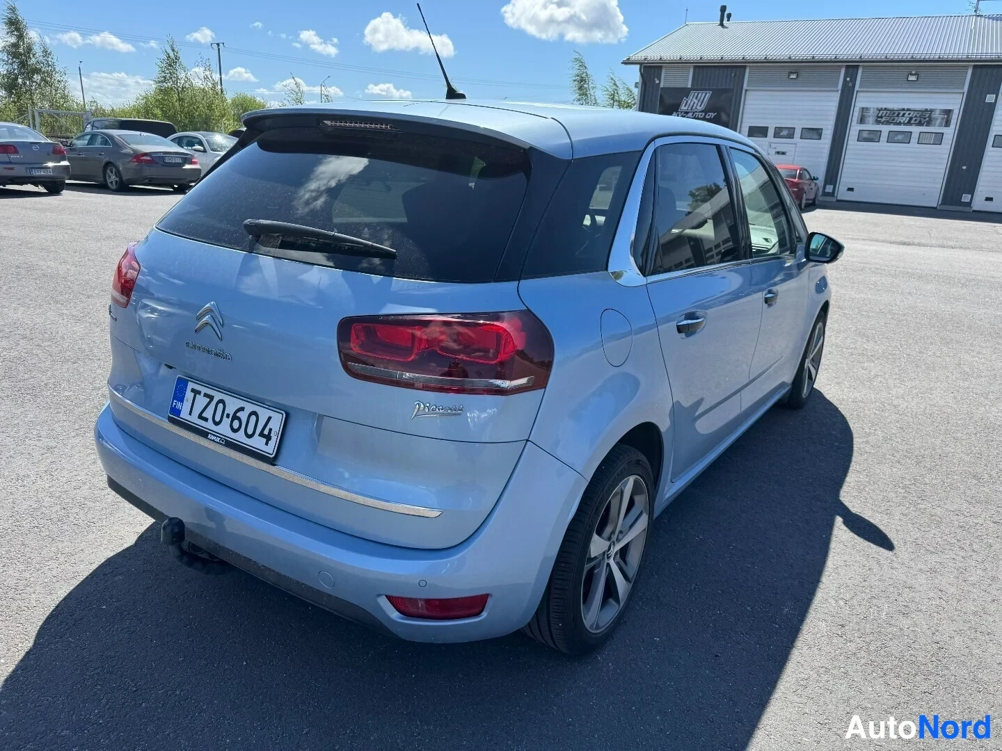 Takaviisto: Vaaleansininen Citroen C4 Picasso takaviistosta, takaovat ja takavalo näkyvissä, vetokoukku takapuskurissa.