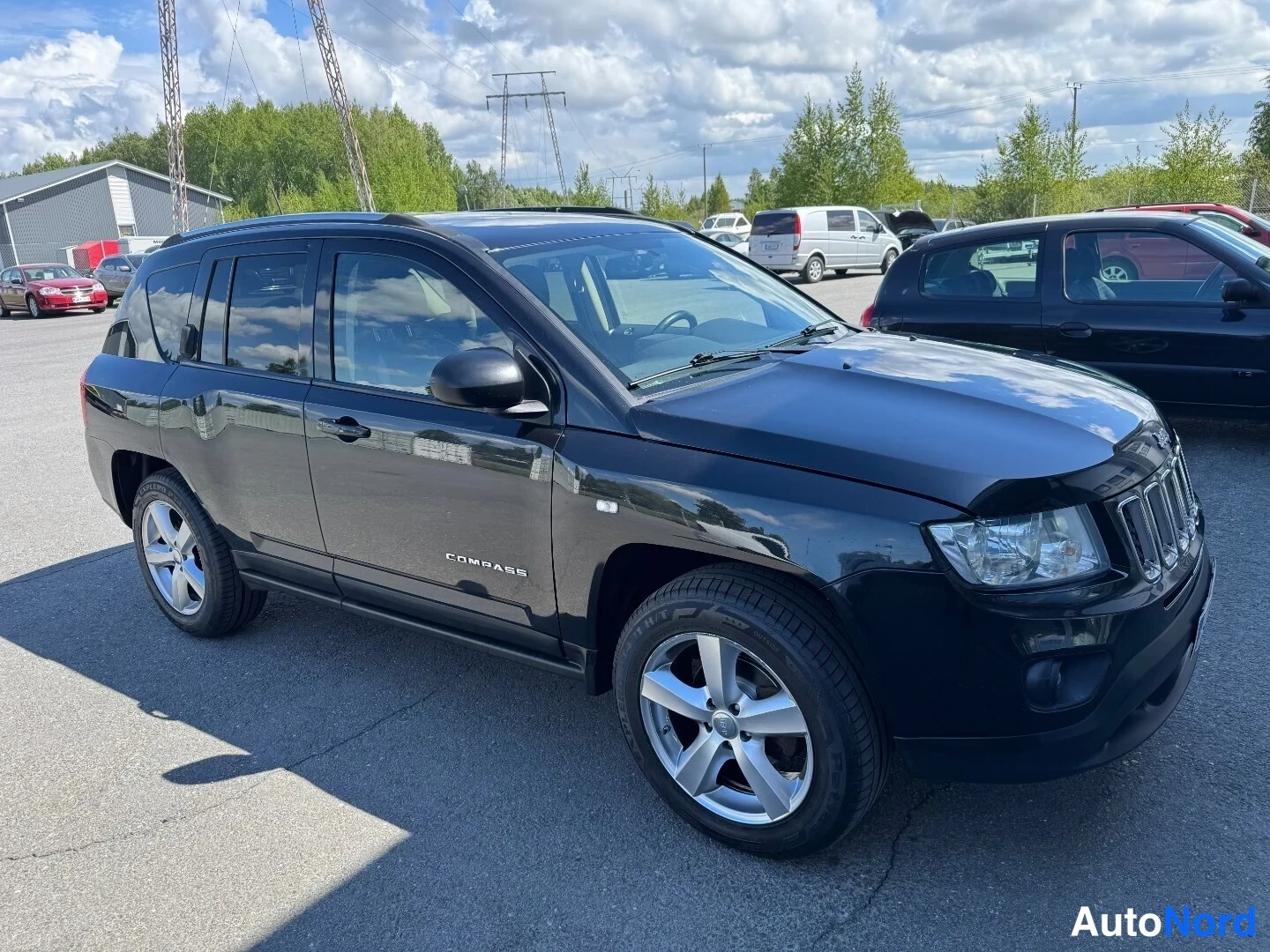 Etuviisto, nokka oikealle: Musta Jeep Compass kulmasta oikealta, kyljessä COMPASS-teksti, hopeiset kevytmetallivanteet.