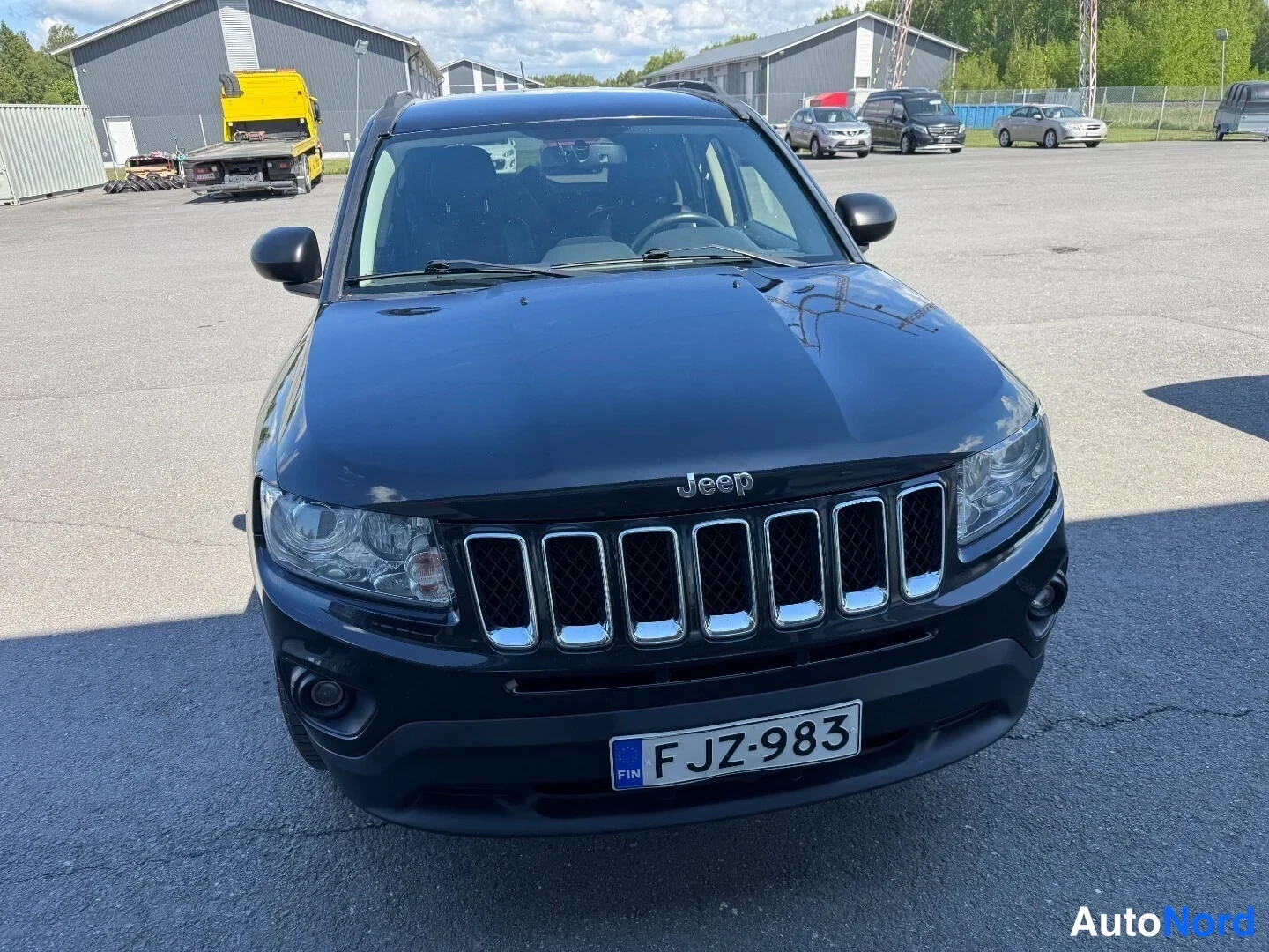 Edestä: Mustan Jeep Compassin etunäkymä, Jeep-merkki ja kromikehystetty etusäleikkö, rekisteri.