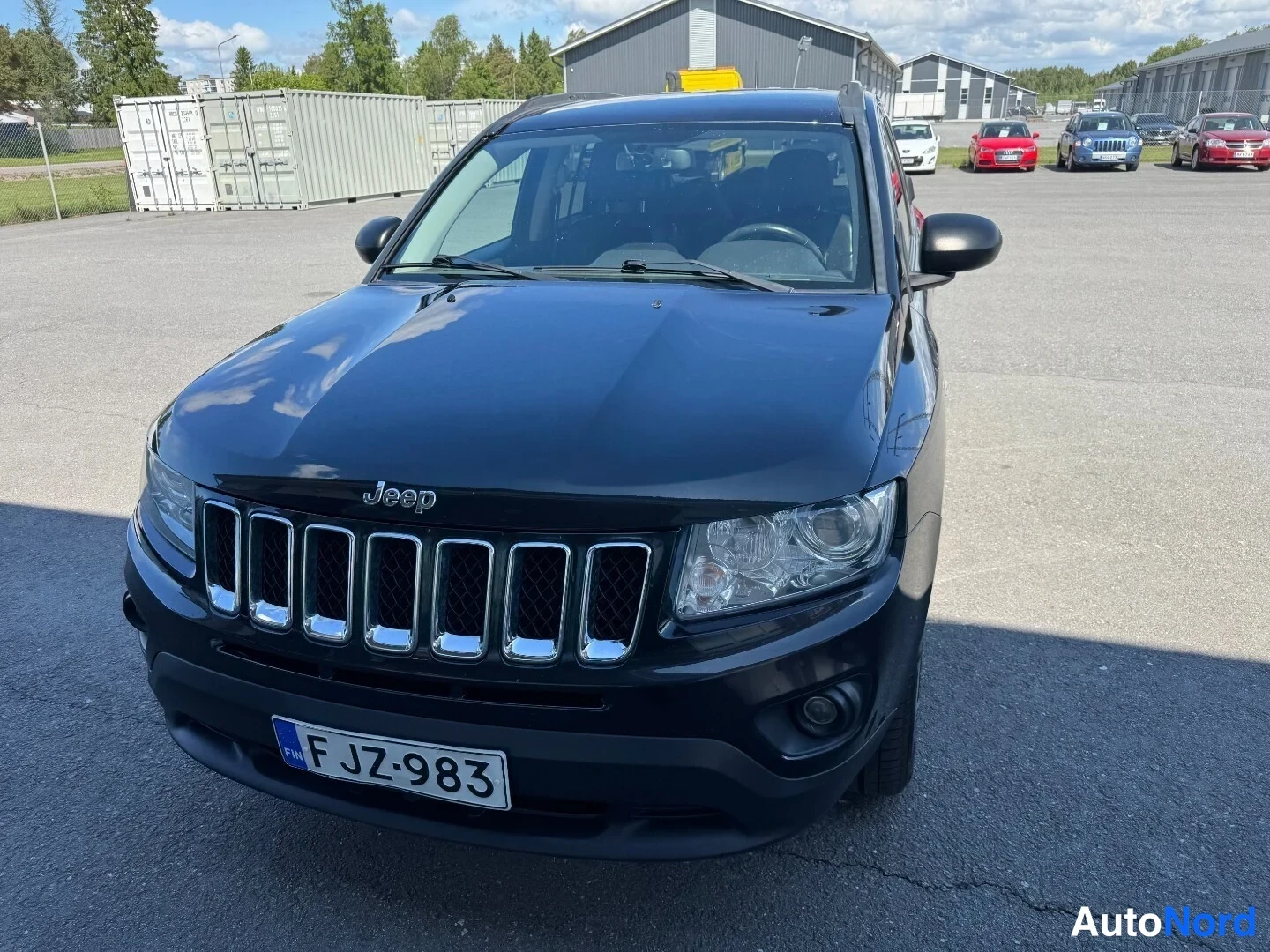 Edestä: Mustan Jeep Compassin etunäkymä läheltä, Jeep-merkki, sumuvalot ja rekisteri.