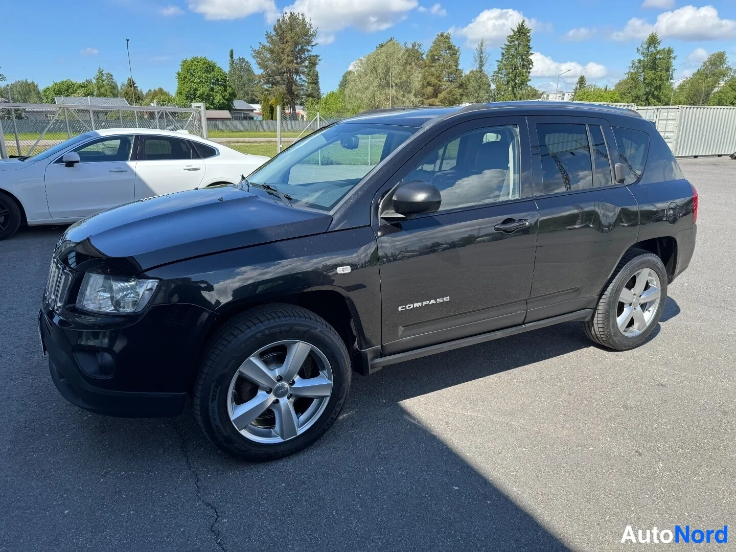 Etuviisto, nokka vasemmalle: Musta Jeep Compass -henkilöauto etu­kolmannes­näkymässä kulmassa, COMPASS-kylkiteksti ja hopeavanteet näkyvät.