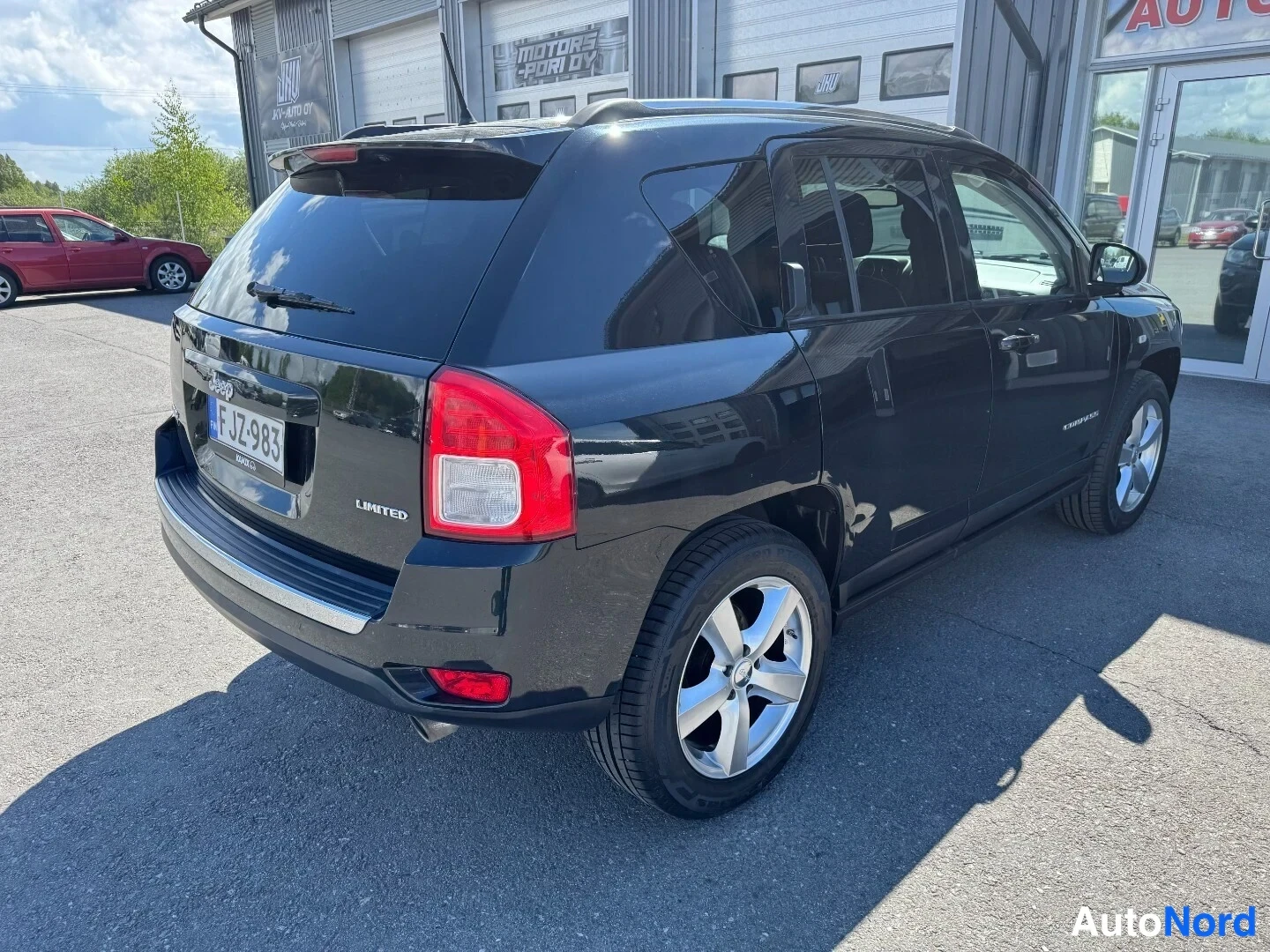 Takaviisto: Musta Jeep Compass Limited -henkilöauto takakolmannes­näkymässä, rekisterikilpi F JZ-983, LIMITED-teksti takapaneelissa ja hopeavanteet näkyvät autotallin ovien