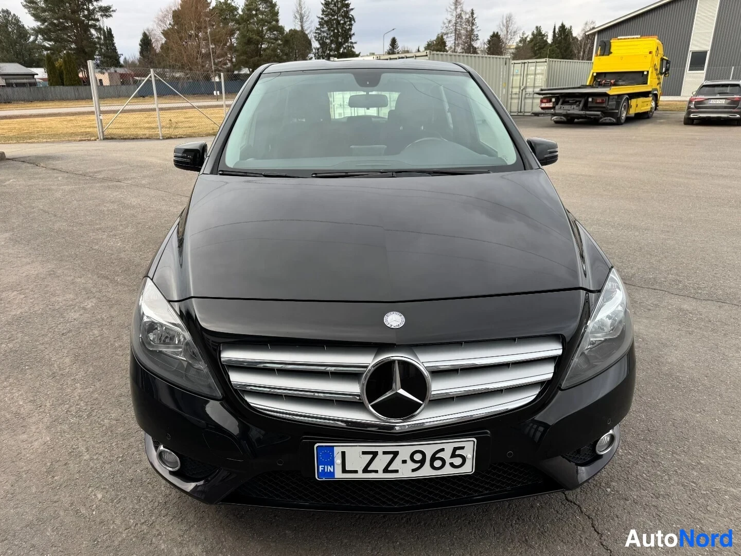 Edestä: Mustan Mercedes-Benz B-luokan henkilöauton suora etunäkymä, rekisterikilpi.