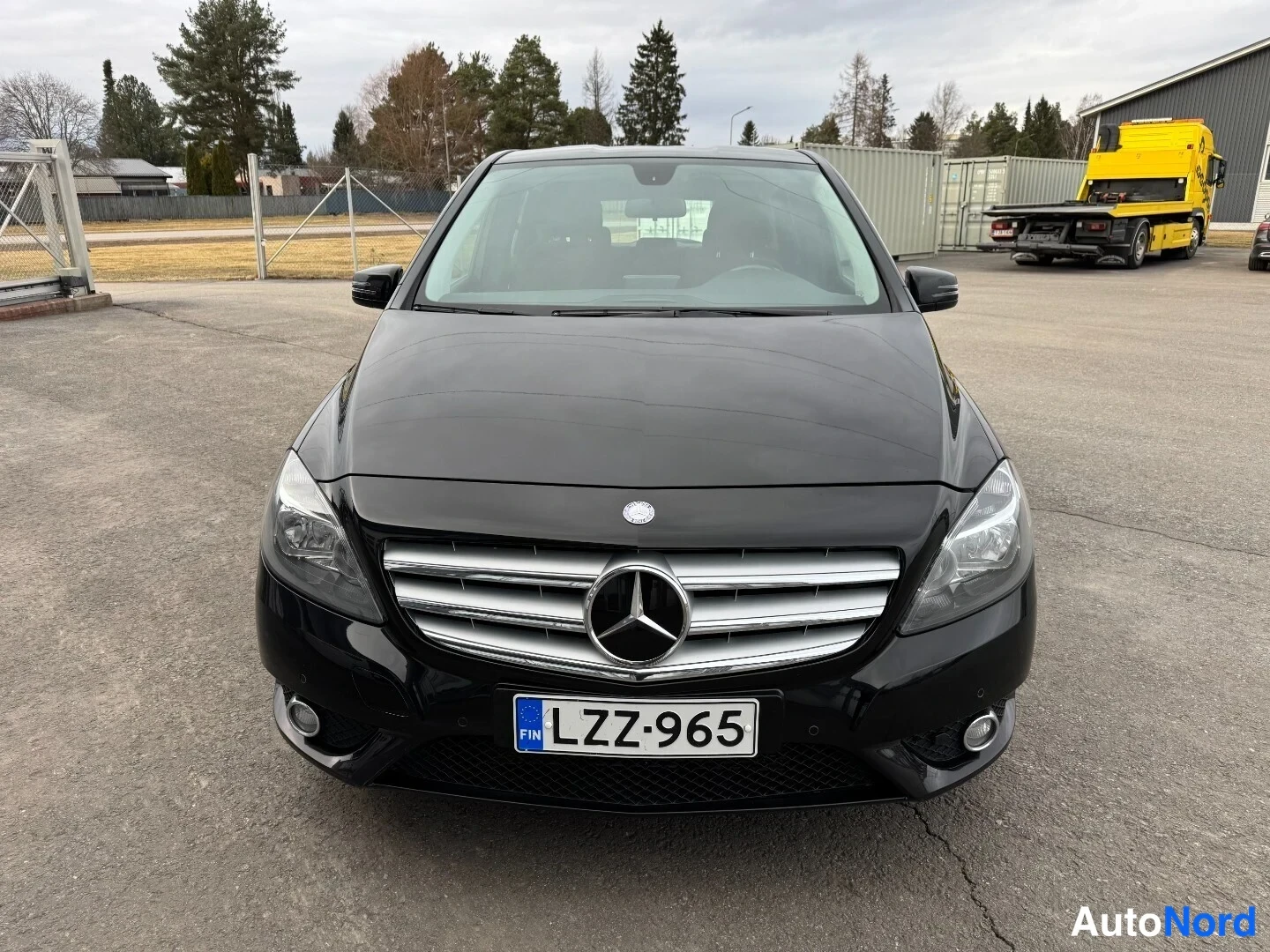 Edestä: Mustan Mercedes-Benz B-luokan henkilöauton suora etunäkymä, rekisterikilpi.
