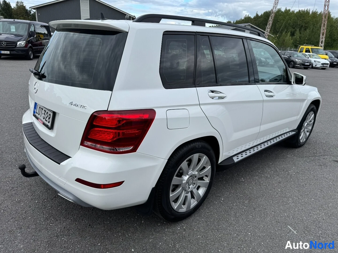 Takaviisto: Mercedes-Benz GLK takaapäin oikealta kyljeltä kuvattuna; valkoinen kori, kromattujen ovikahvojen kiiltävä pinta, kattokaiteet ja kylkiastimet.