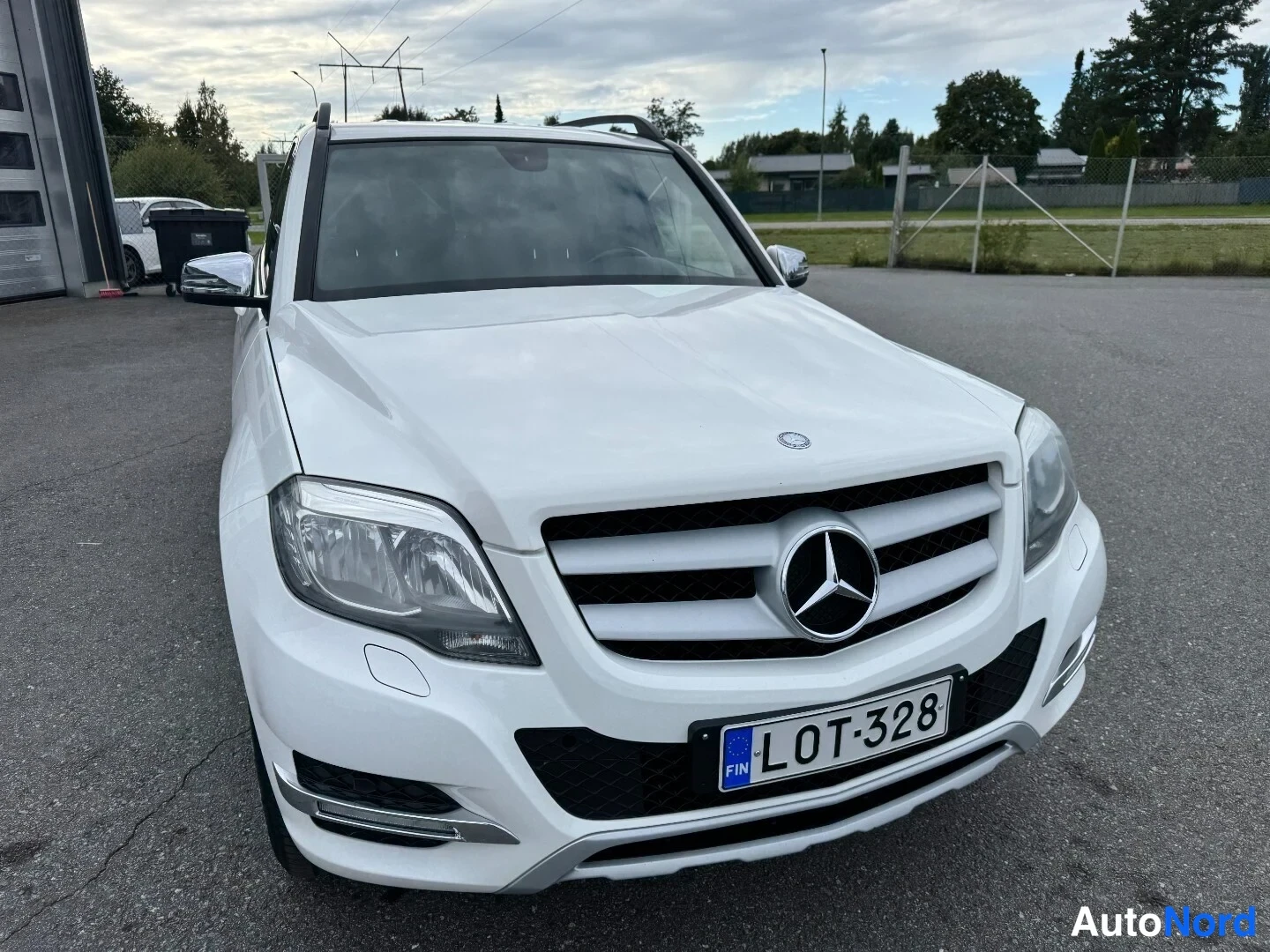 Edestä: Mercedes-Benz GLK:n etukuva suoraan edestä, valkoinen koriväri, etusäleikkö ja Mercedes-tähti, rekisteritunnus.