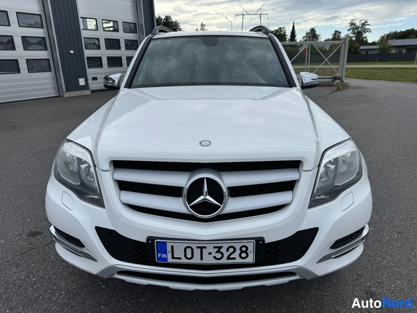 Edestä: Mercedes-Benz GLK:n etukuva suoraan edestä, valkoinen koriväri, etusäleikkö ja Mercedes-tähti, rekisteritunnus.