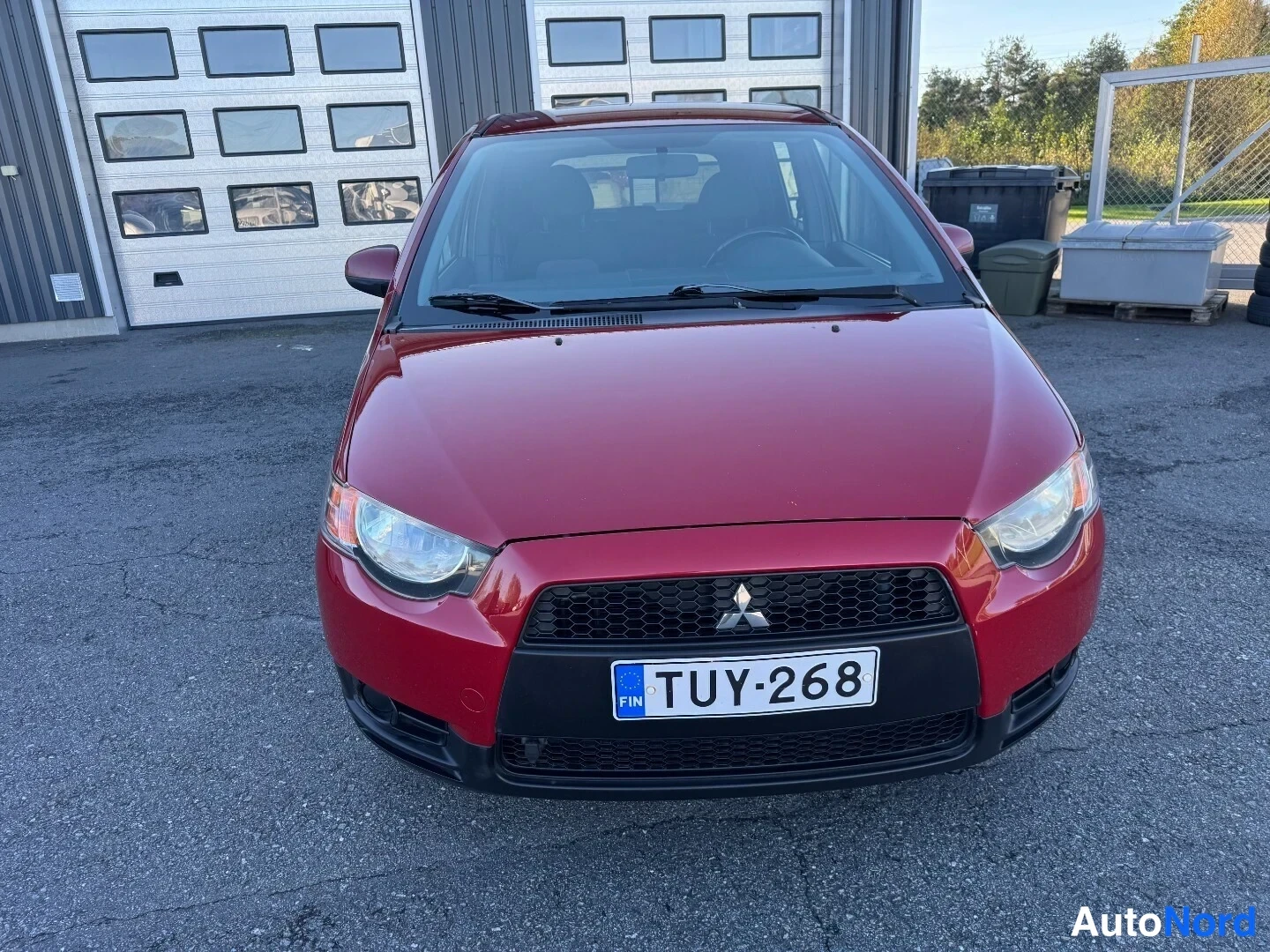 Edestä: Punainen Mitsubishi Colt suoraan edestä, rekisteritunnus, konepelti- ja etupuskulika vastaanottokuvassa.