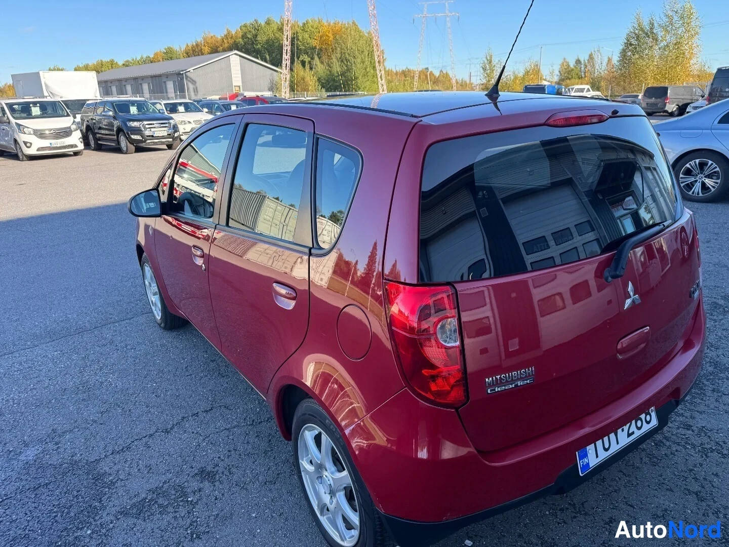 Takaviisto: Punaisen Mitsubishi Colt -auton takakolmasosan kuva takapäältä oikealta, rekisterikilpi, MITSUBISHI ClearTec -teksti takaluukussa.