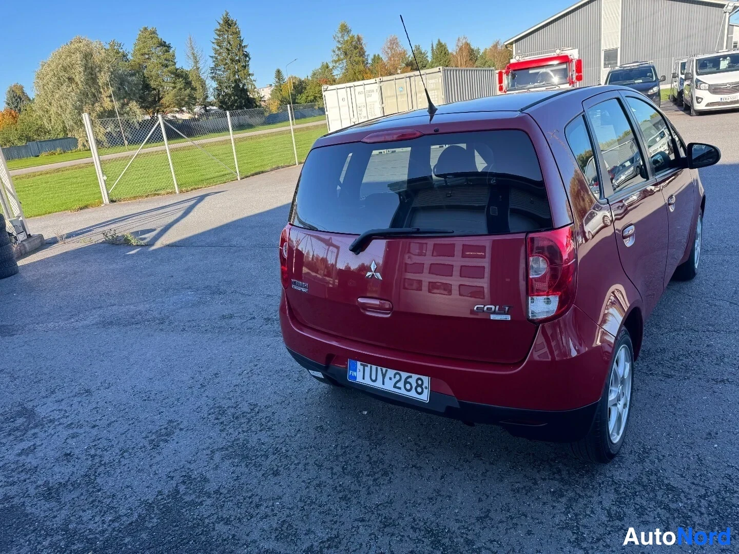 Takaviisto: Punaisen Mitsubishi Colt -auton takakolmasosan kuva takapäältä vasemmalta, rekisterikilpi ja COLT-teksti takaluukussa.