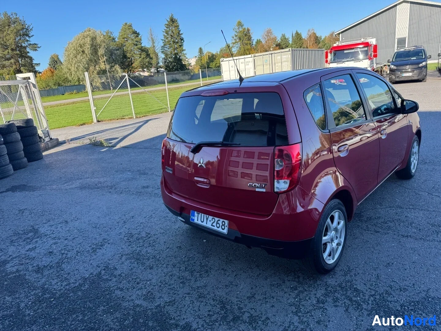 Takaviisto: Punaisen Mitsubishi Colt -auton takakolmasosan kuva takapäältä vasemmalta, rekisterikilpi, takaluukussa COLT-teksti.