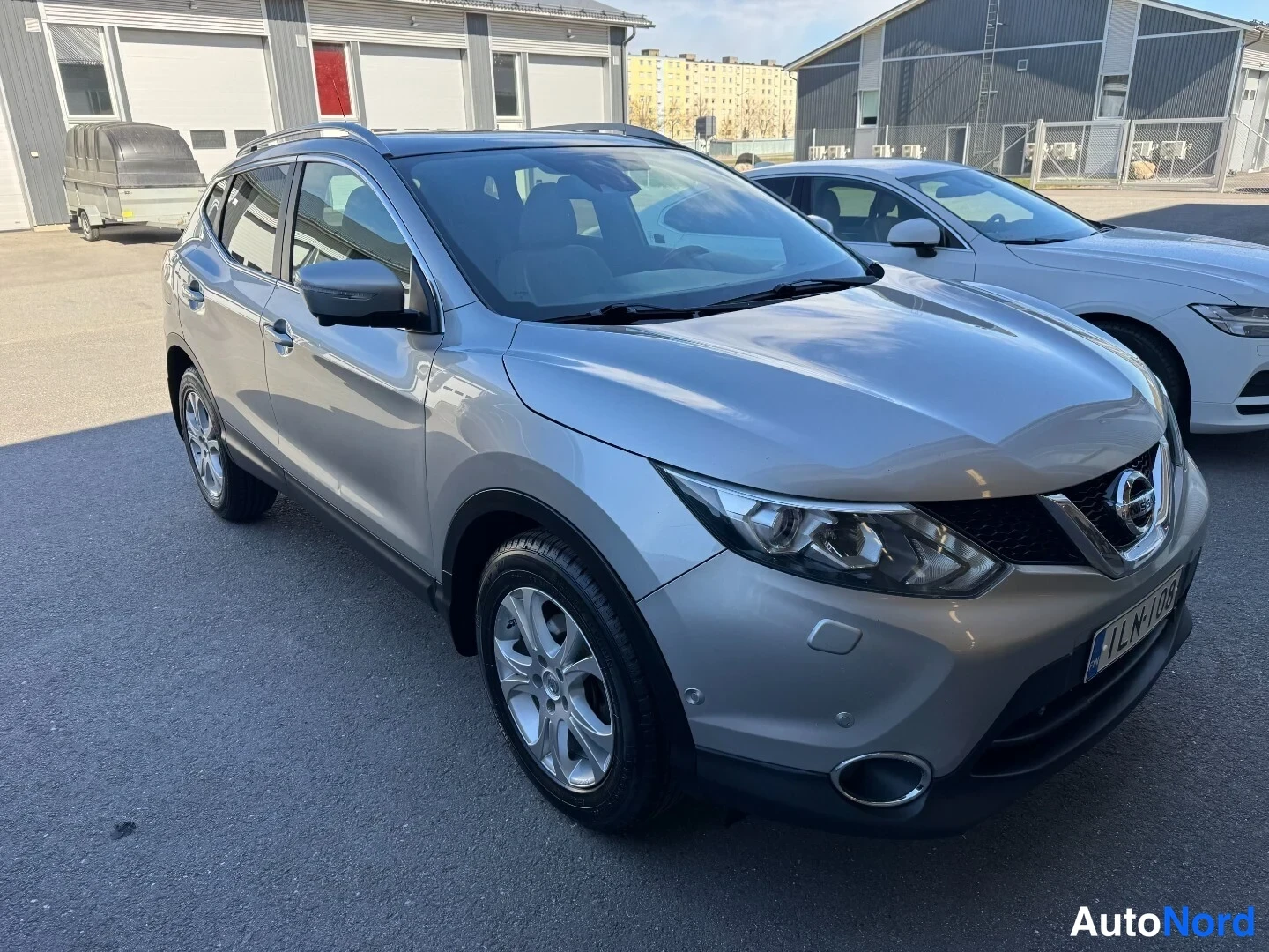 Etuviisto, nokka oikealle: Hopeanharmaa Nissan Qashqai -maastoauto kulmakuva edestä oikealta, rekisteritunnus.