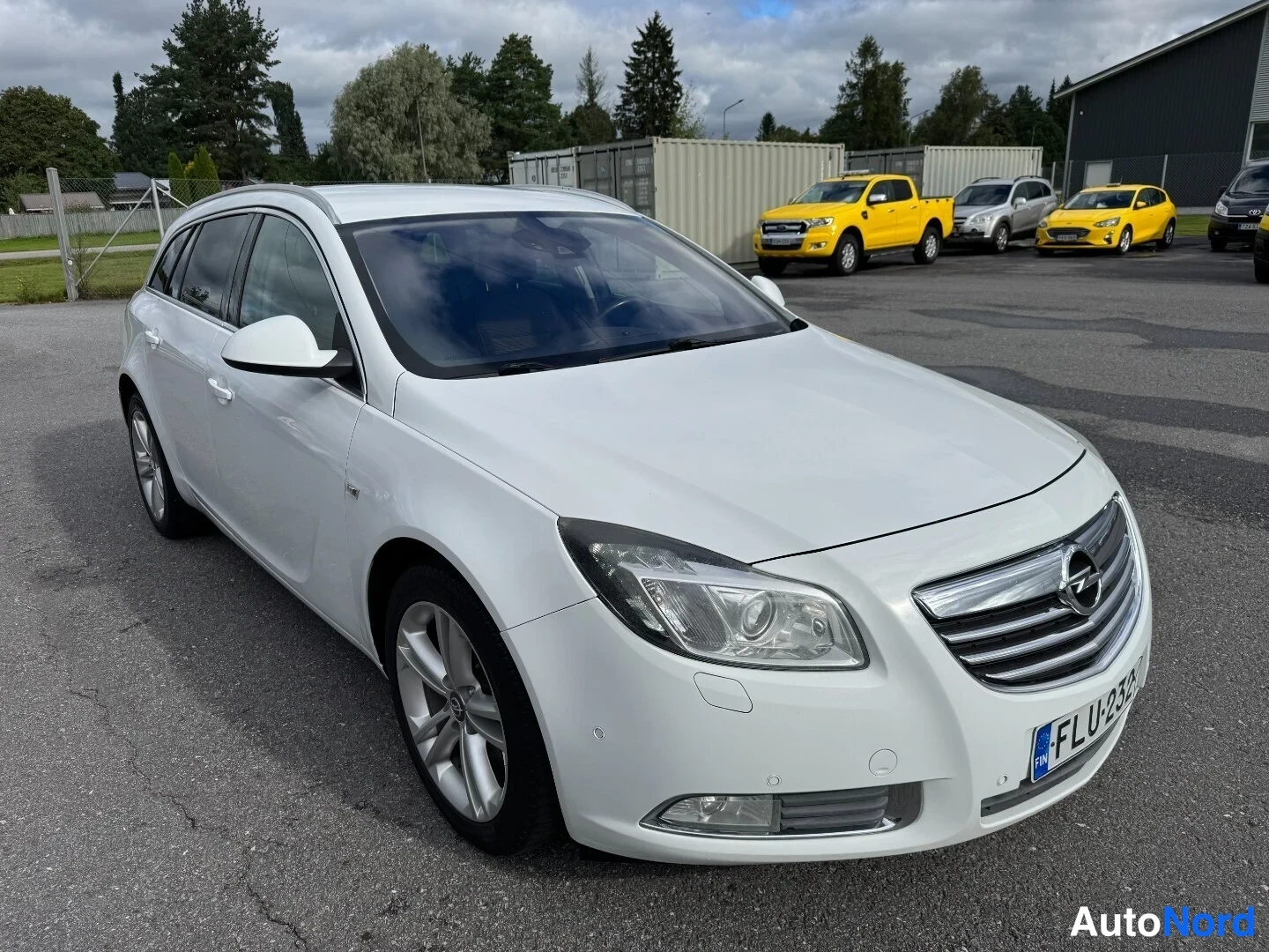 Etuviisto, nokka oikealle: Valkoinen Opel Insignia -farmariauto valokuvattu kolmasosaedestä oikealta, konepellin ja etusäleikön sekä oikean kyljen ollessa näkyvissä.