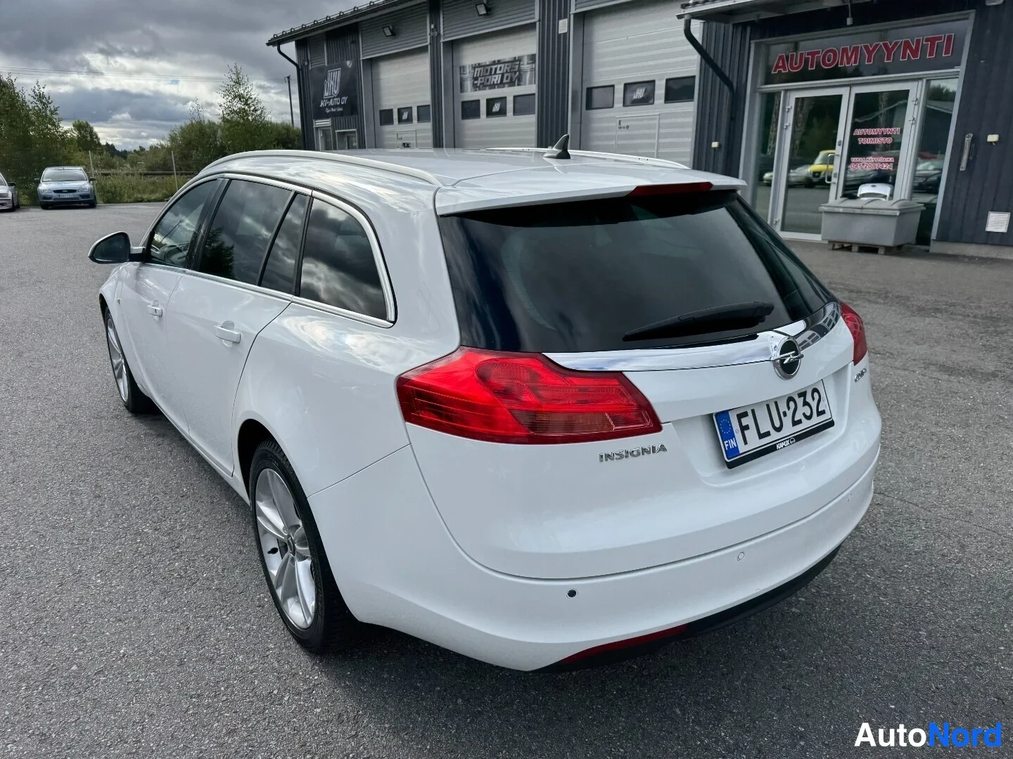 Takaviisto: Valkoisen Opel Insignia -farmarin takakulma; takaluukussa teksti INSIGNIA, Opel-tunnus ja rekisterikilpi näkyvissä.