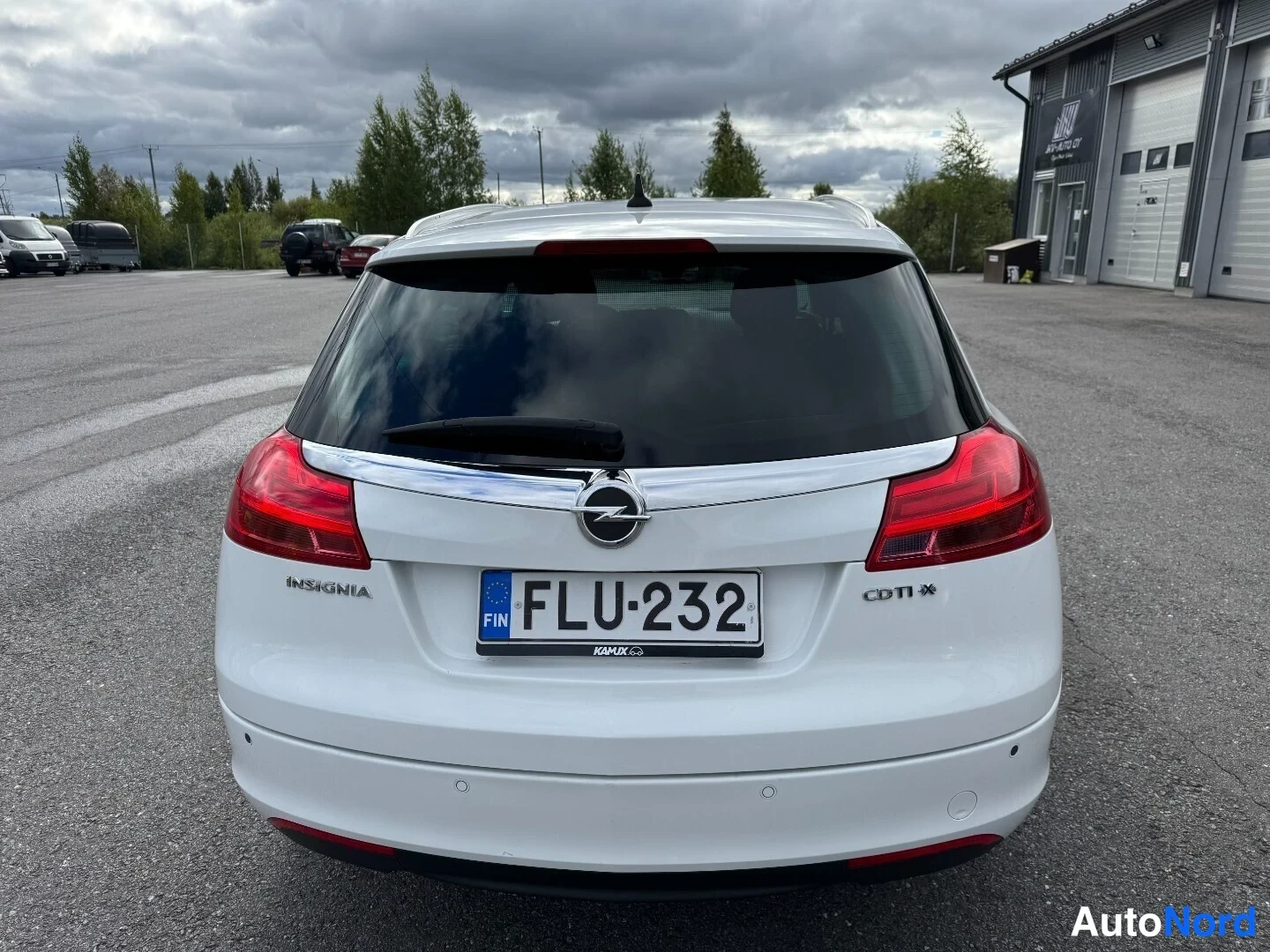 Takaa: Valkoisen farmariauto takaa kuvattu; takaluukussa Opel Insignia -merkintä ja rekisterikilpi, ylhäällä kattoteline.