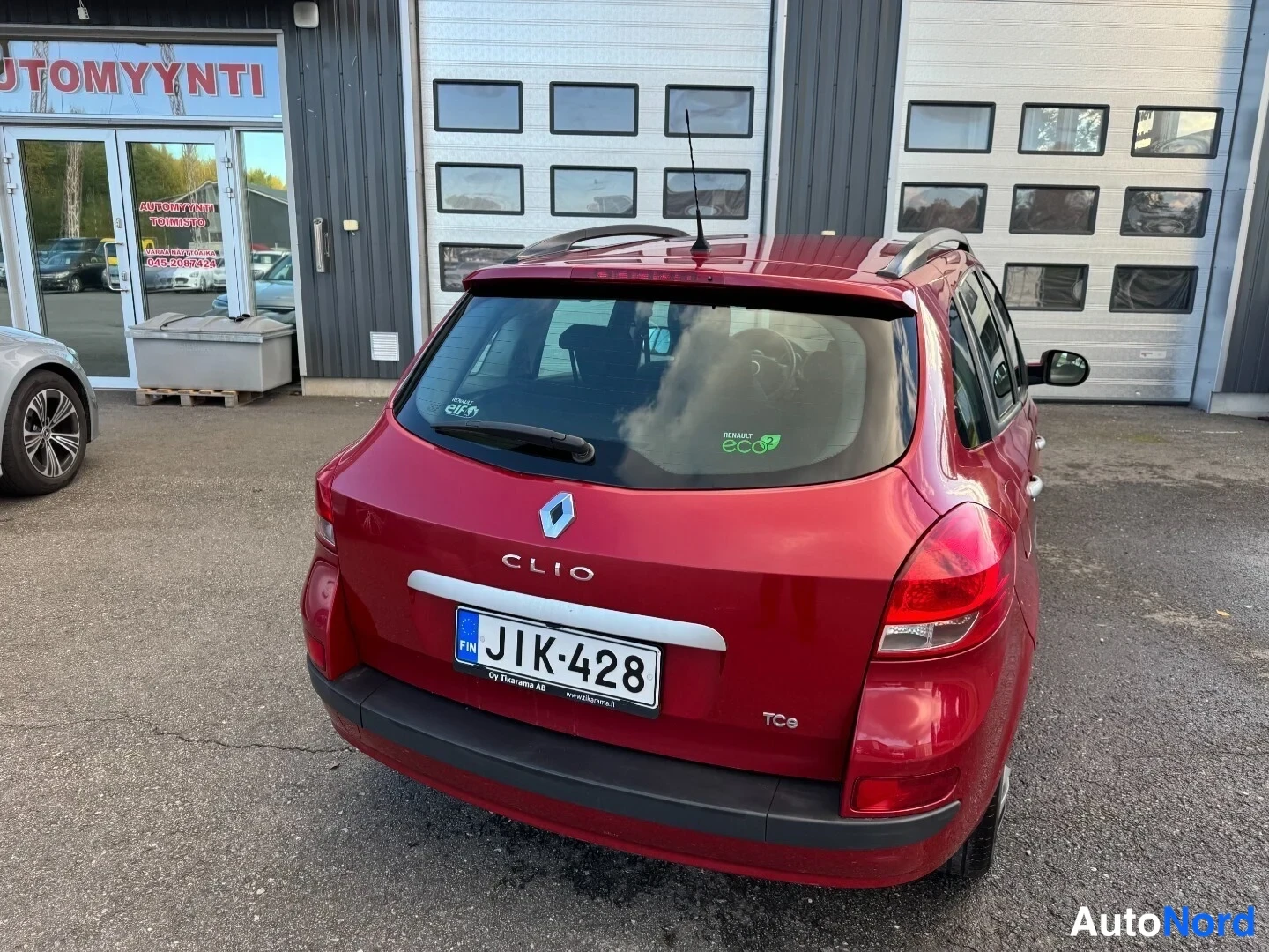 Takaviisto: Punaisen Renault Clion takaosa suoraan takaapäin, rekisterikilpi ja eco-tarra takalasissa.
