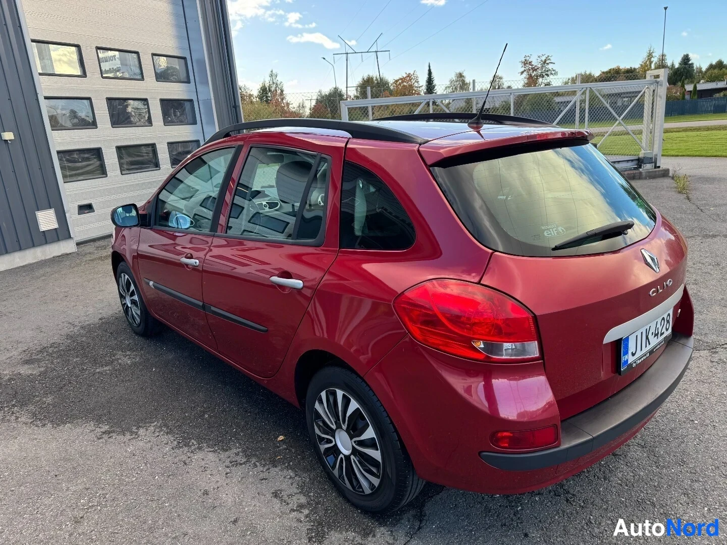 Takaviisto: Punainen Renault Clio Tourer -farmari takaa- ja vasemmalta päin kuvattuna; näkyvissä kattokaiteet, ovenkahvat ja takavalot.