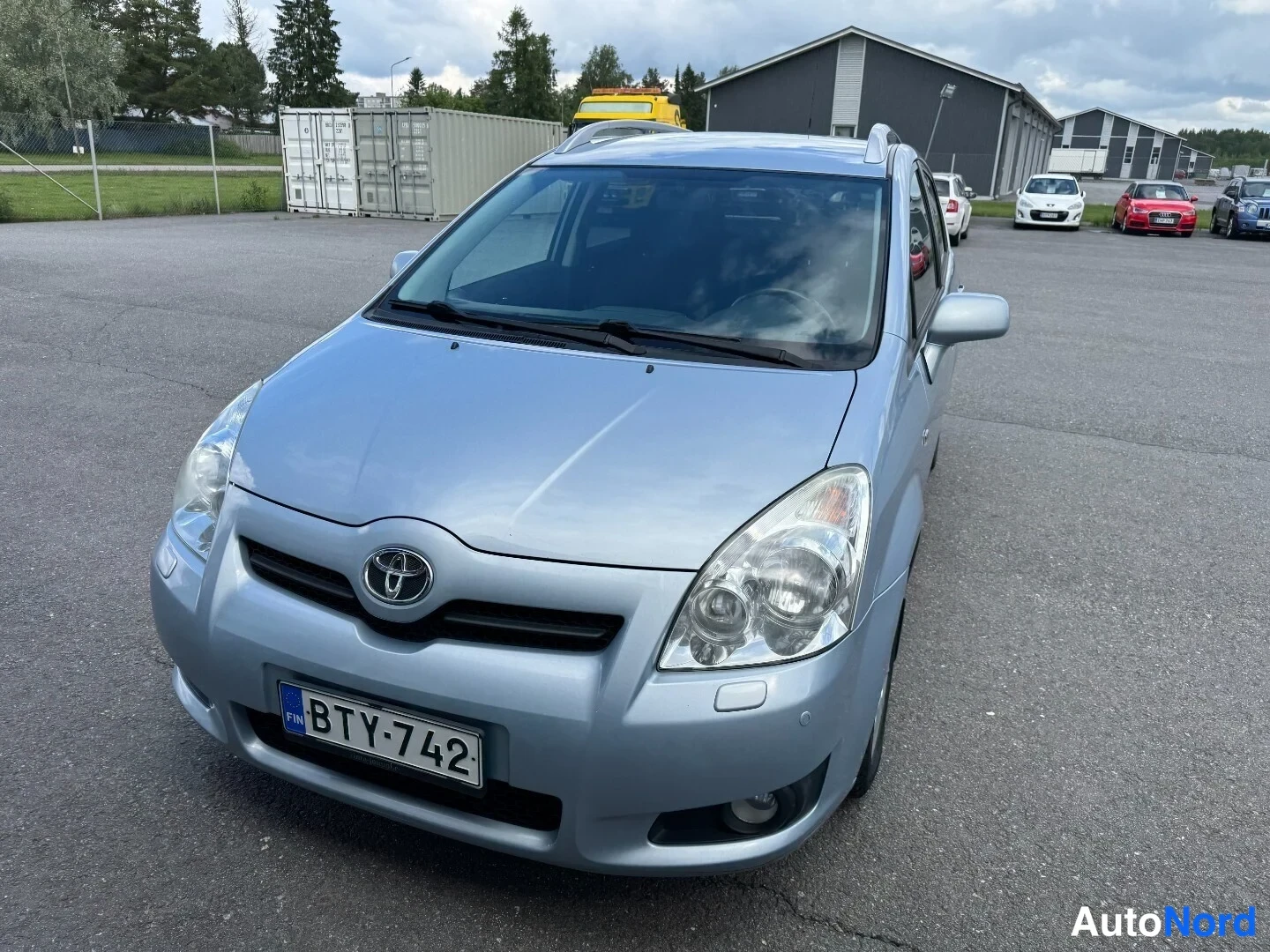 Etuviisto, nokka vasemmalle: Vaaleansininen Toyota Corolla Verso suoraan edestäpäin hieman viistosti, rekisteritunnus.
