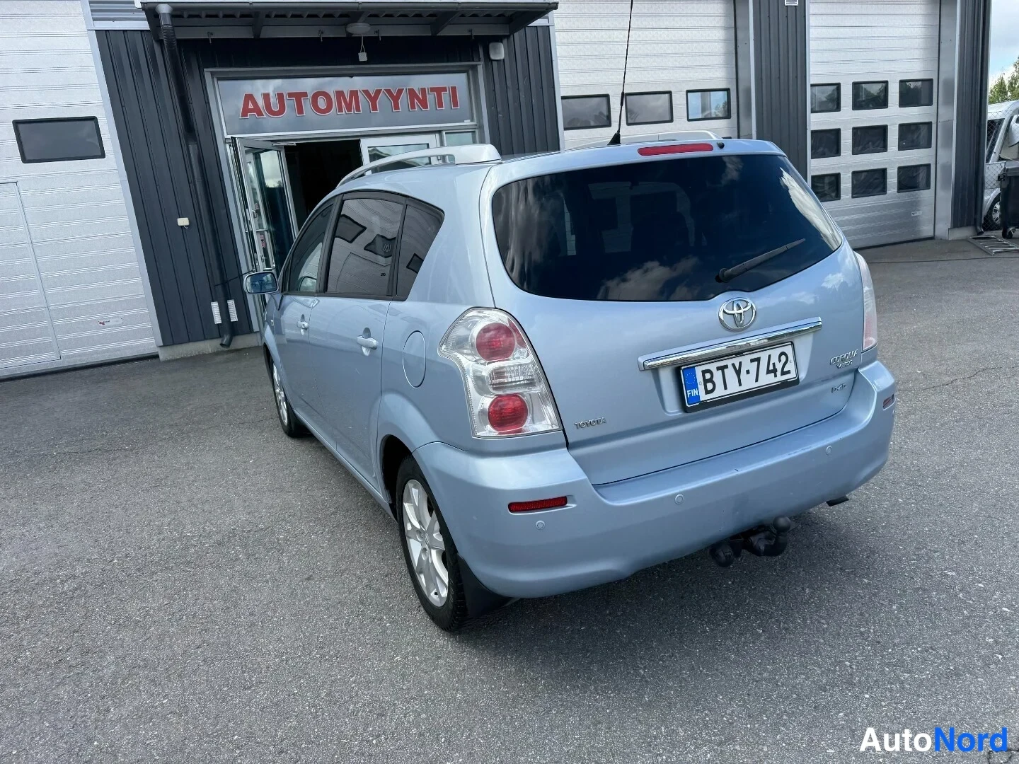 Takaviisto: Toyota Corolla Verso takaa viistosti oikealta, vaaleansininen farmariminivanAutoSize rekisterillä.