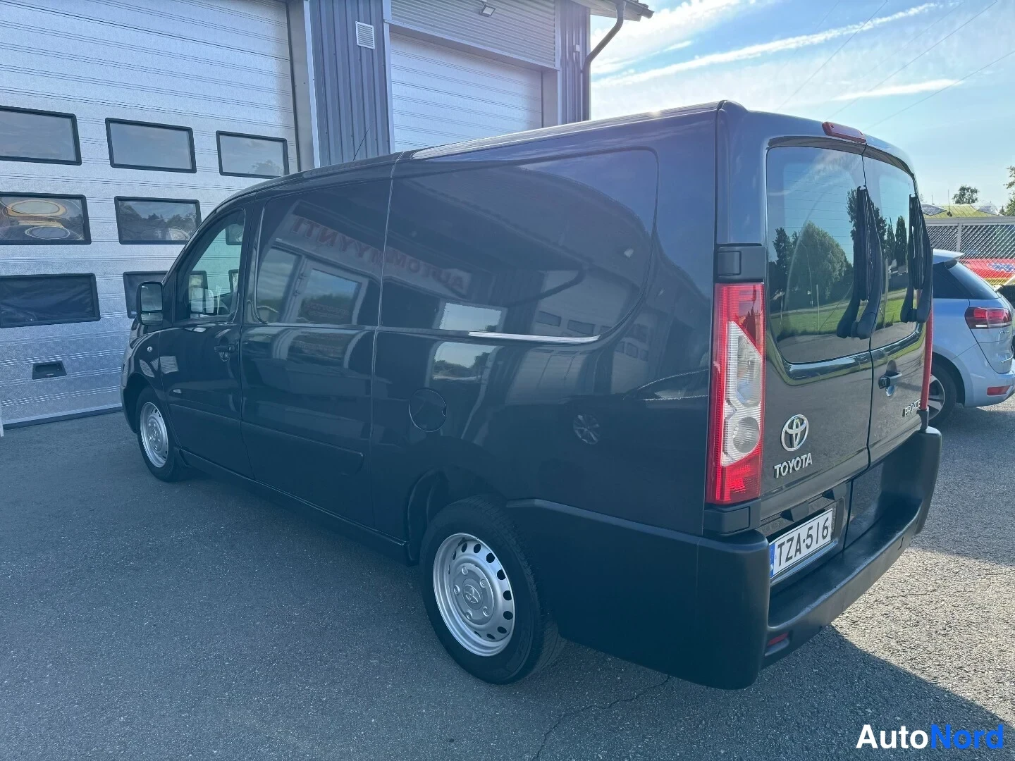 Takaviisto: Tummanharmaa Toyota Proace taka­viistosta vasemmalta, peräovet ja Toyota-merkki näkyvät, rekisteri.