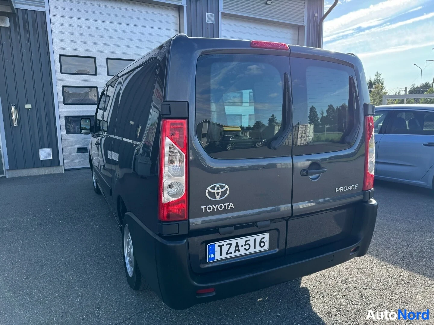 Takaviisto: Tummanharmaan Toyota Proace -pakettiauton takapää ja vasen kylki takaa kuvattuna; rekisteritunnus.