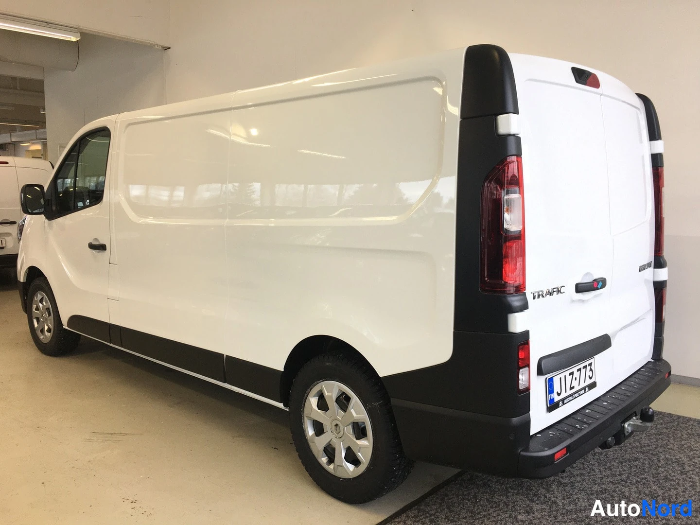 Takaviisto: Renault Trafic -pakettiauto takaa vasemmalta, valkoinen koripaneelein, musta takapuskuri ja Trafic-merkintä peräluukussa.