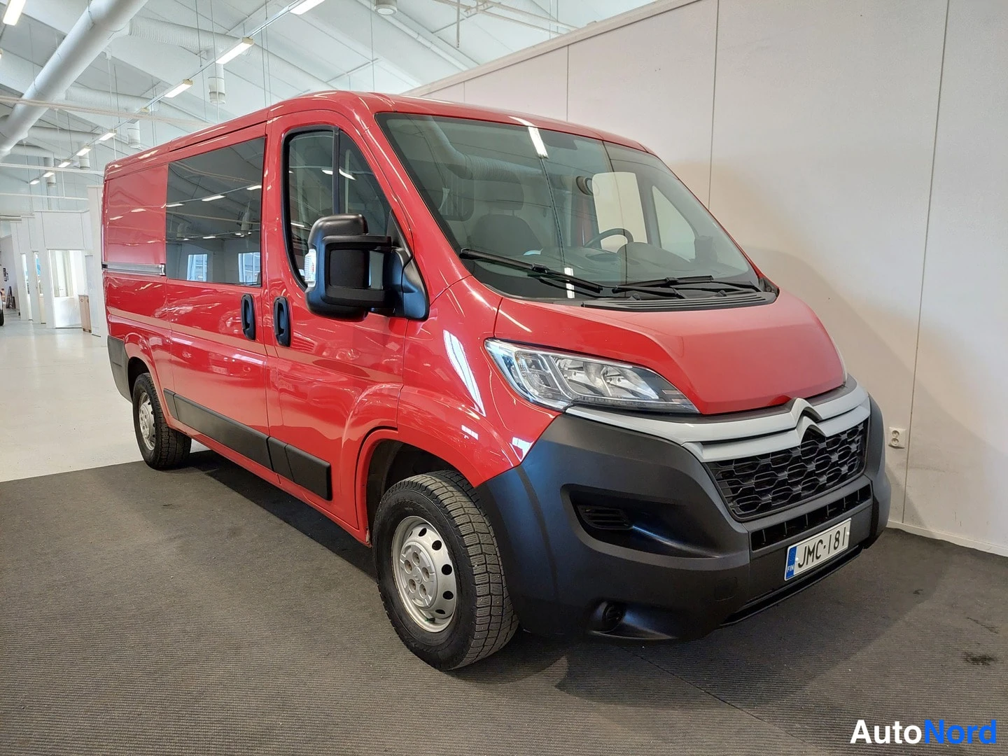 Etuviisto, nokka oikealle: Punainen Citroen Jumper pakettiauto etukulmassa oikealta, rekisterikilpi, sisätilassa.