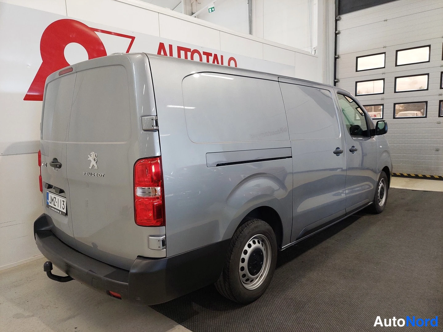 Takaviisto: Pakettiauton takakulmanäyttö: hopeanharmaa Peugeot Expert, avattava takaluukku, punaiset takavalot, musta puskuri ja pieni vetokoulu, rekisteri.