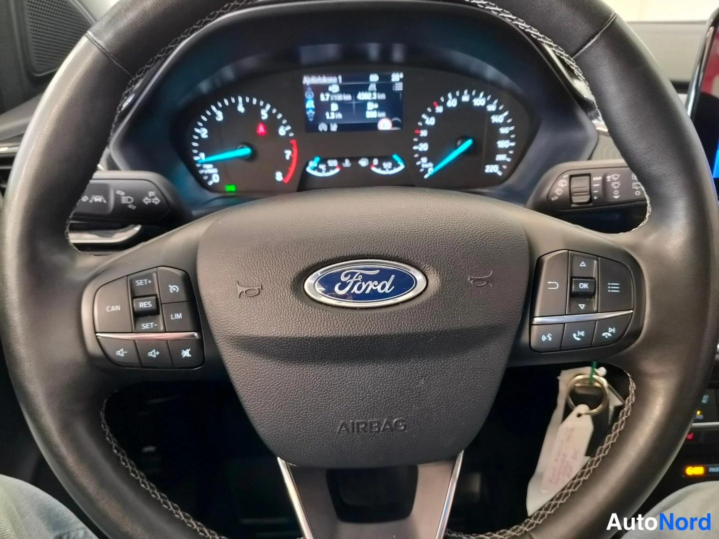Muu: Fordin ohjauspyörä lähikuvassa, Ford-merkki ja AIRBAG-teksti, taustalla mittaristo.