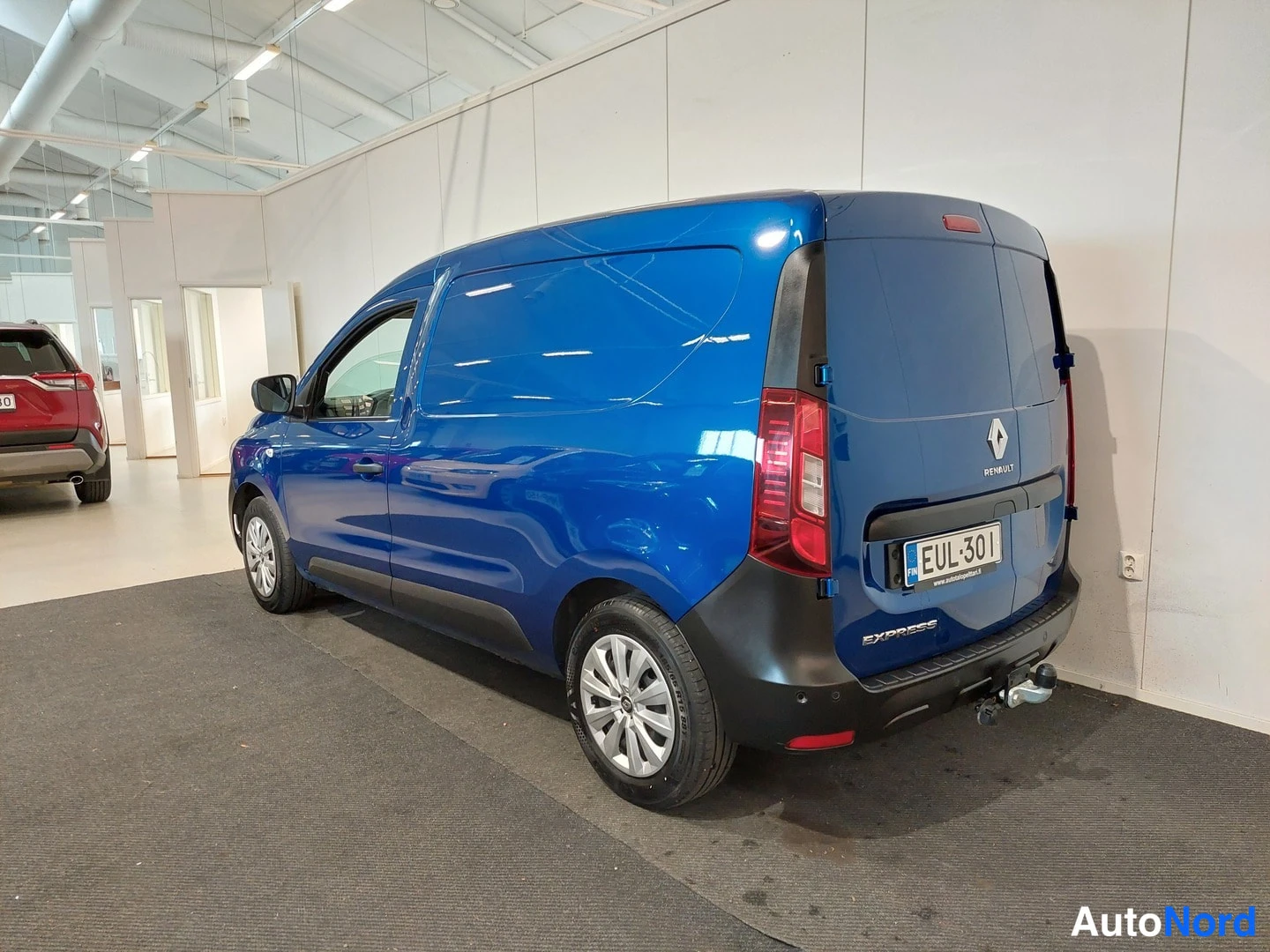 Takaviisto: Sininen pakettiauto kuvattuna takaa kulmasta; peräovessa Renault-merkki ja teksti EXPRESS, rekisterikilpi ja perässä vetokoukku.