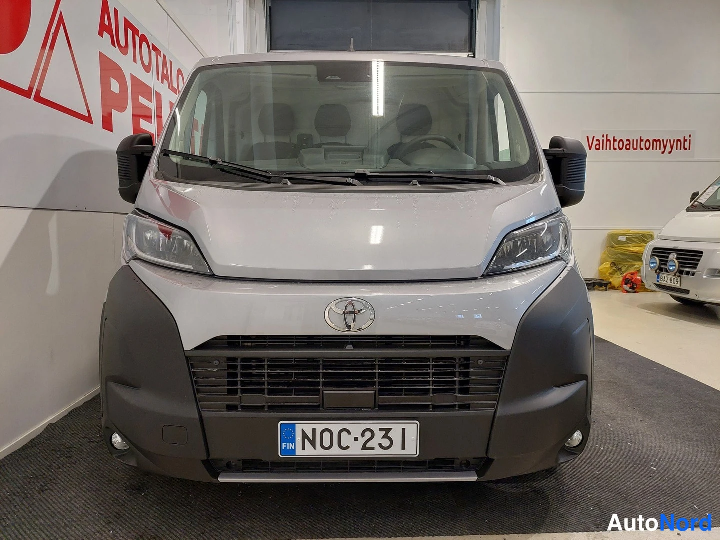 Edestä: Toyota Proace MAXin etupää suoraan edestä valaistussa sisätilassa; rekisterikilpi