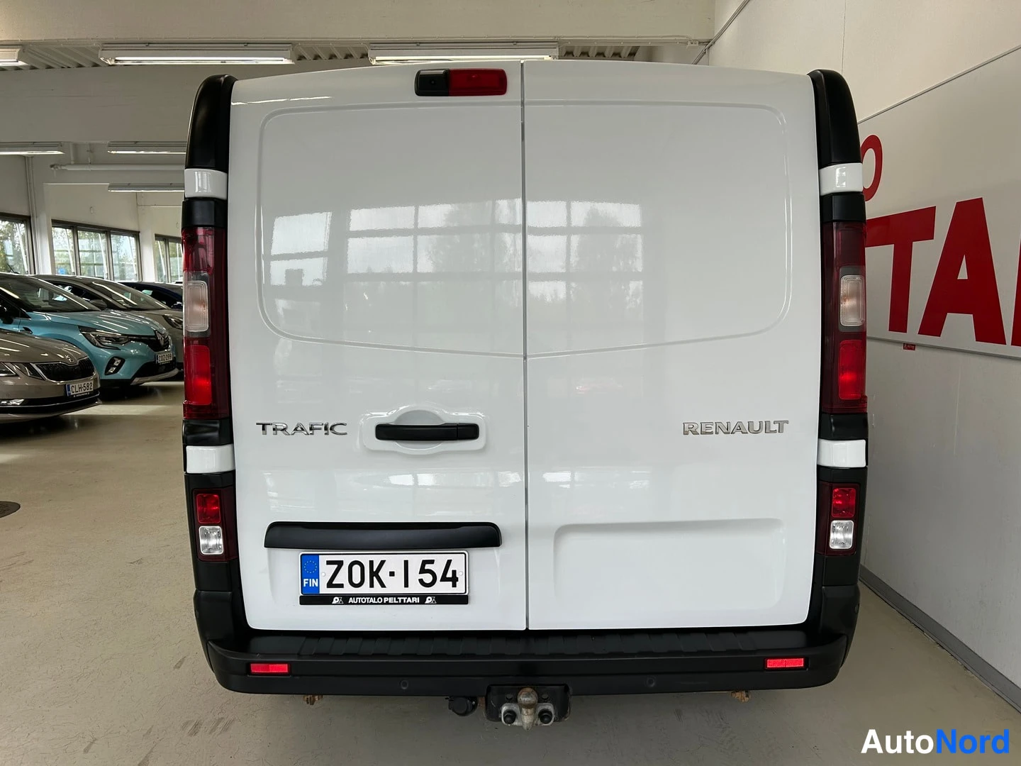 Takaa: Renault Trafic -pakettiauto takaa suoraan kuvattuna; takaluvussa tekstit TRAFIC ja RENAULT, rekisterikilpi ja perävaunukoulu.