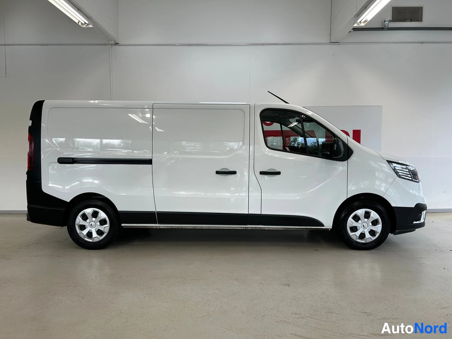 Sivulta: Renault Trafic -pakettiauto sivulta kuvattuna, valkoinen kori, liukuova sivuovi ja mustat puskurit.