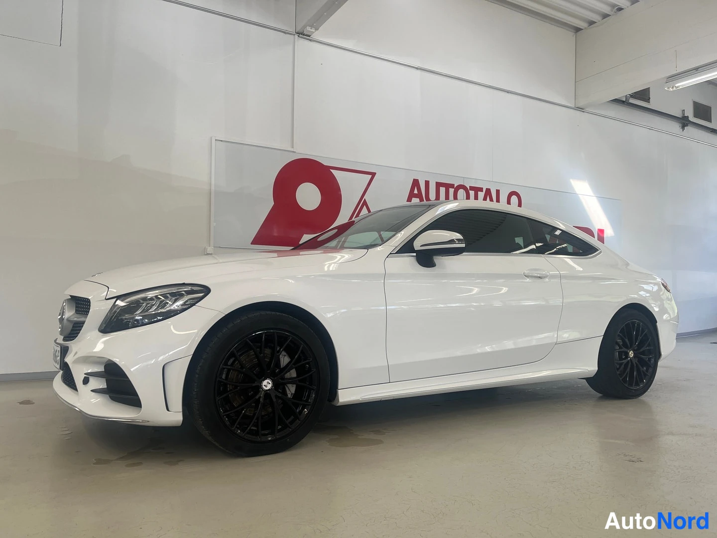 Etuviisto: Valkoinen kaksiovinen coupé-tyylinen Mercedes-Benz etuoso-kulmakuvassa vasemmalla; mustat kevytmetallivanteet, kromikehyksinen etusäleikkö ja tyyliviiva koriin.