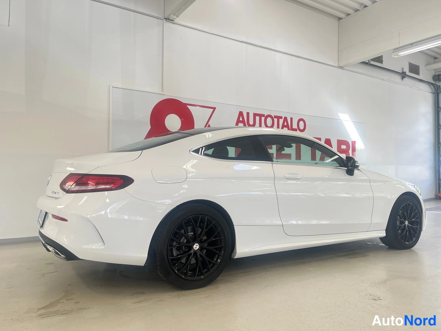 Takaviisto: Valkoinen Mercedes-Benz C-coupé takaviistosta kuvattuna autotallissa; mustat kevytmetallivanteet.