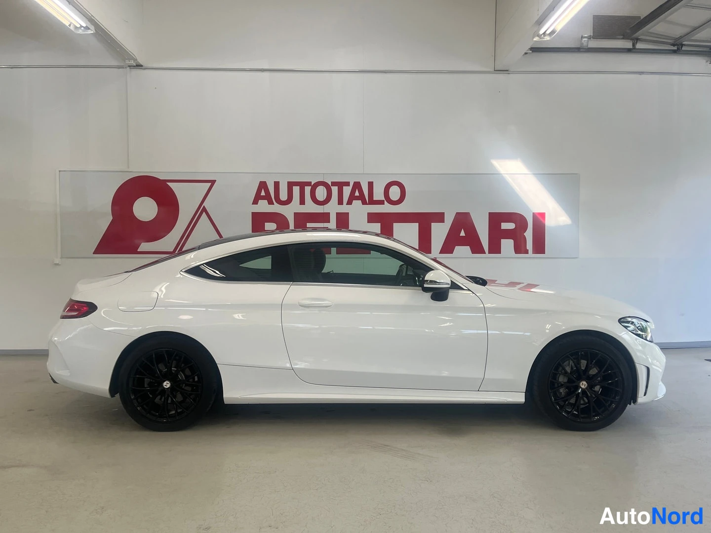 Sivulta: Valkoinen Mercedes-Benz C-coupé sivusta kuvattuna; mustat kevytmetallivanteet ja tumma katto.