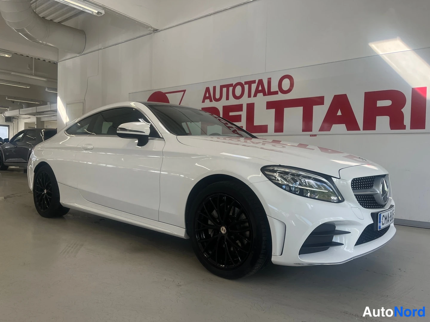 Etuviisto, nokka oikealle: Valkoinen Mercedes-Benz C-coupé etuviistosta kuvattuna; keula oikealla, mustat kevytmetallivanteet ja etuvalot näkyvissä.