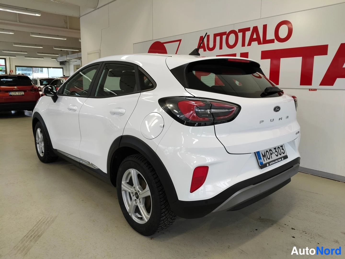 Takaviisto: Valkoinen auto takaa vasemmasta kolmanneskulmasta sisätiloissa, rekisteritunnus.