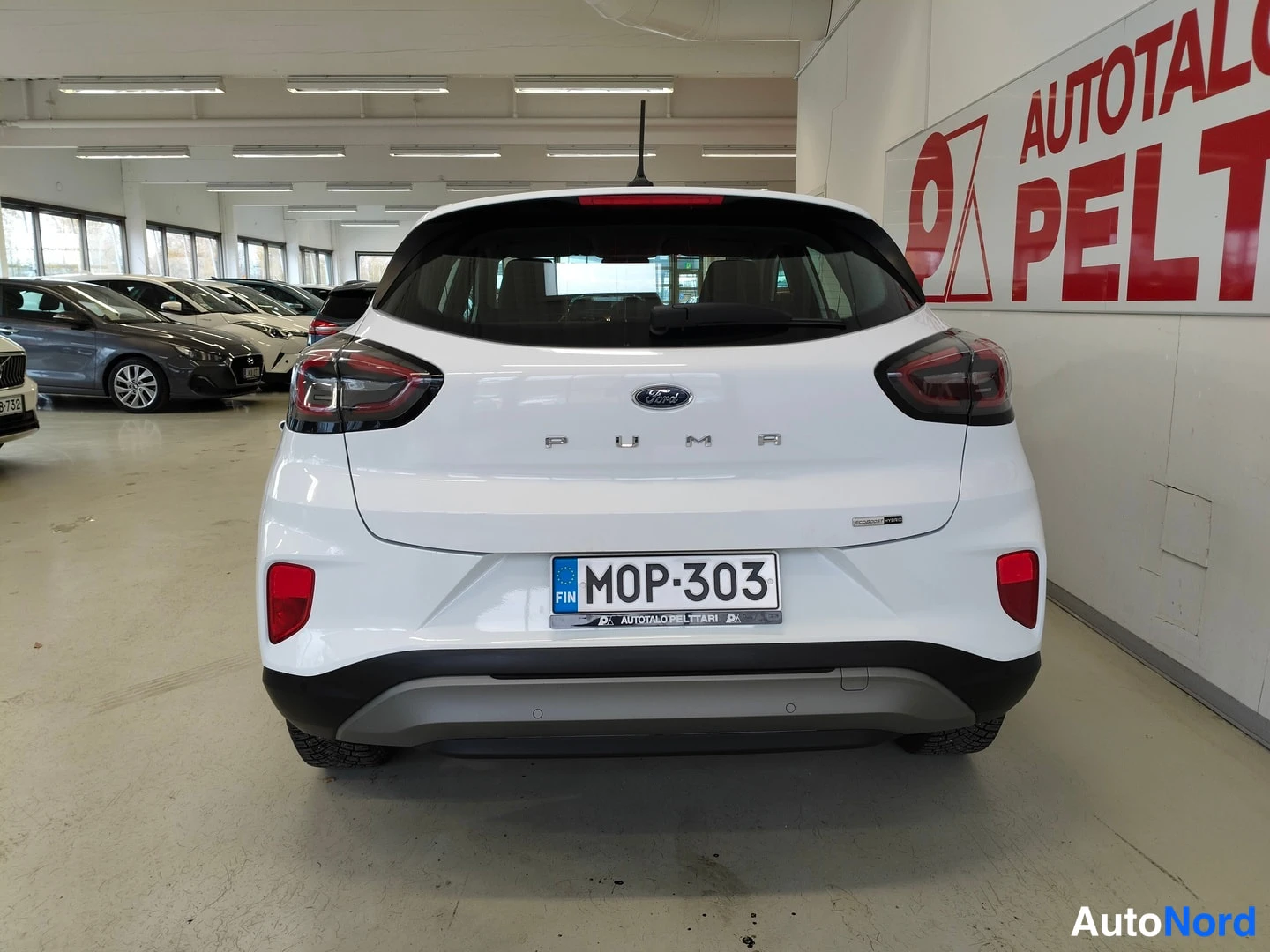 Takaa: Auton takaosa kuvattuna suoraan takaa; valkoinen koripaneeli, Ford-merkki, PUMA-teksti, rekisterikilpi ja tummat takavalot hallitilassa.