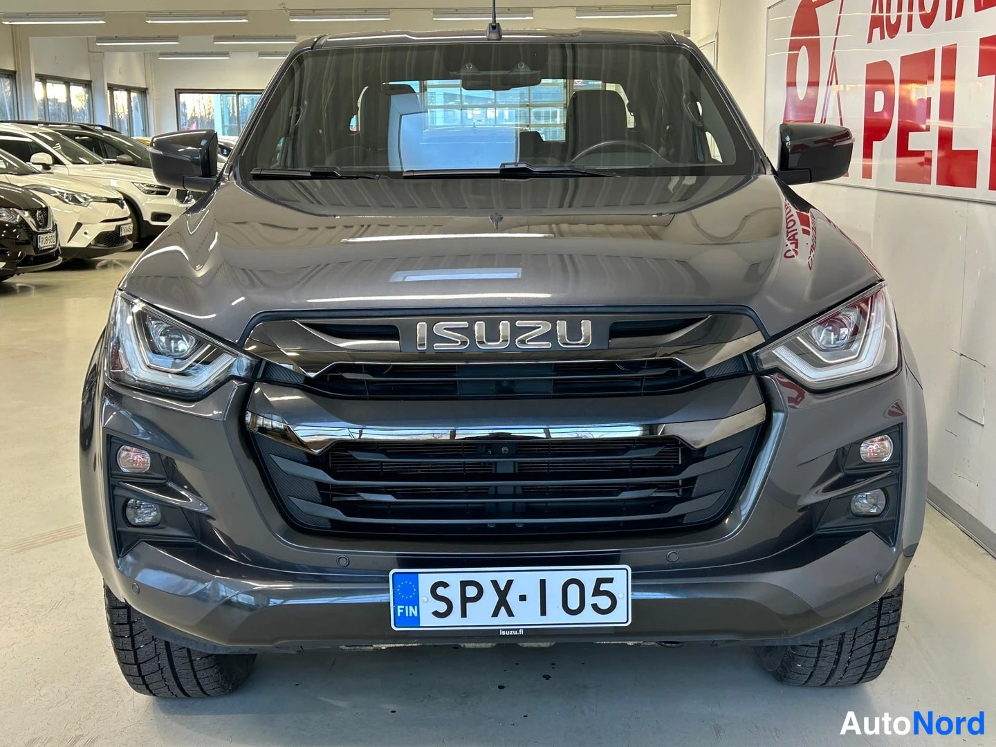 Edestä: Tummanharmaa avolava-auto suoraan edestä kuvattuna; Isuzu-merkintä jäähdyttimen suojukassa.