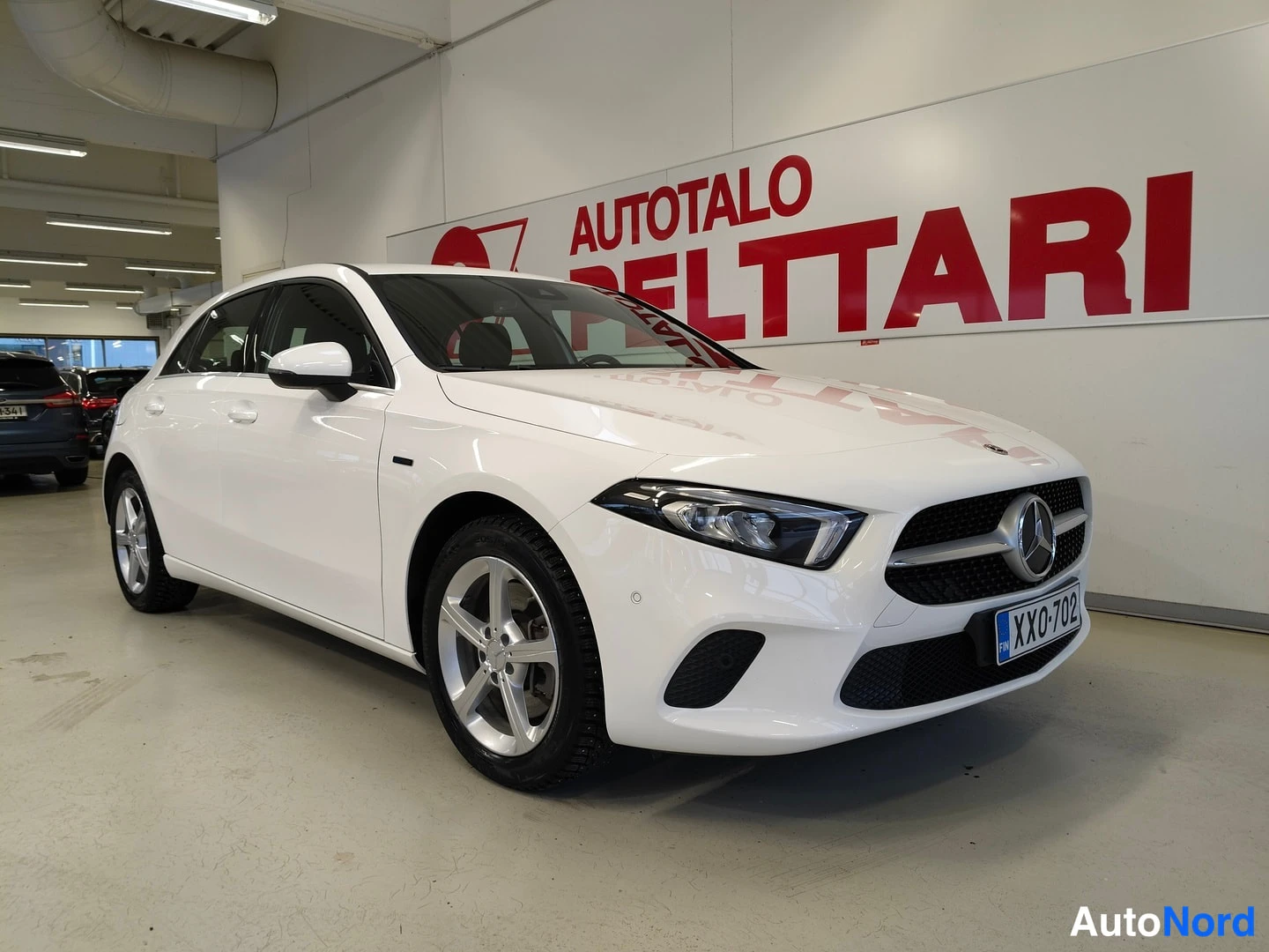 Etuviisto, nokka oikealle: Valkoinen Mercedes-Benz A -hatchback etuviisto näkymä, etusäleikkö ja Mercedes-tähti, rekisterikilpi XX0-702, hopeiset peltivanteet.