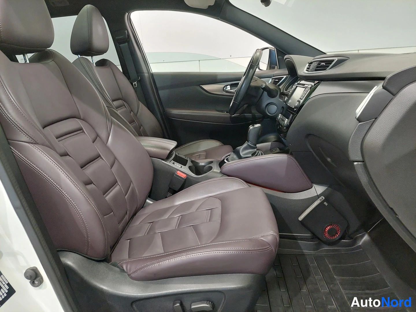 Muu: Nissan Qashqaiin etuistuimet ja kojelauta kuljettajan puolen oven aukosta katsottuna.
