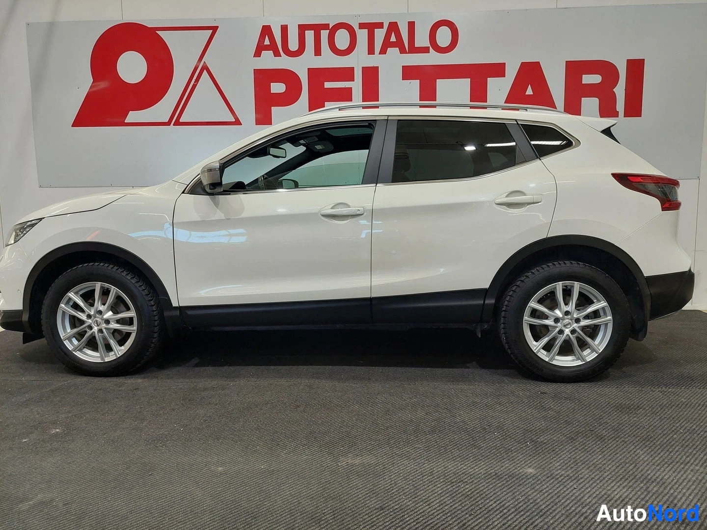 Etuviisto, nokka vasemmalle: Valkoinen Nissan Qashqai -maasturinen etukulmasta, keula vasemmalla, katumaasturi-auto sisätiloissa.