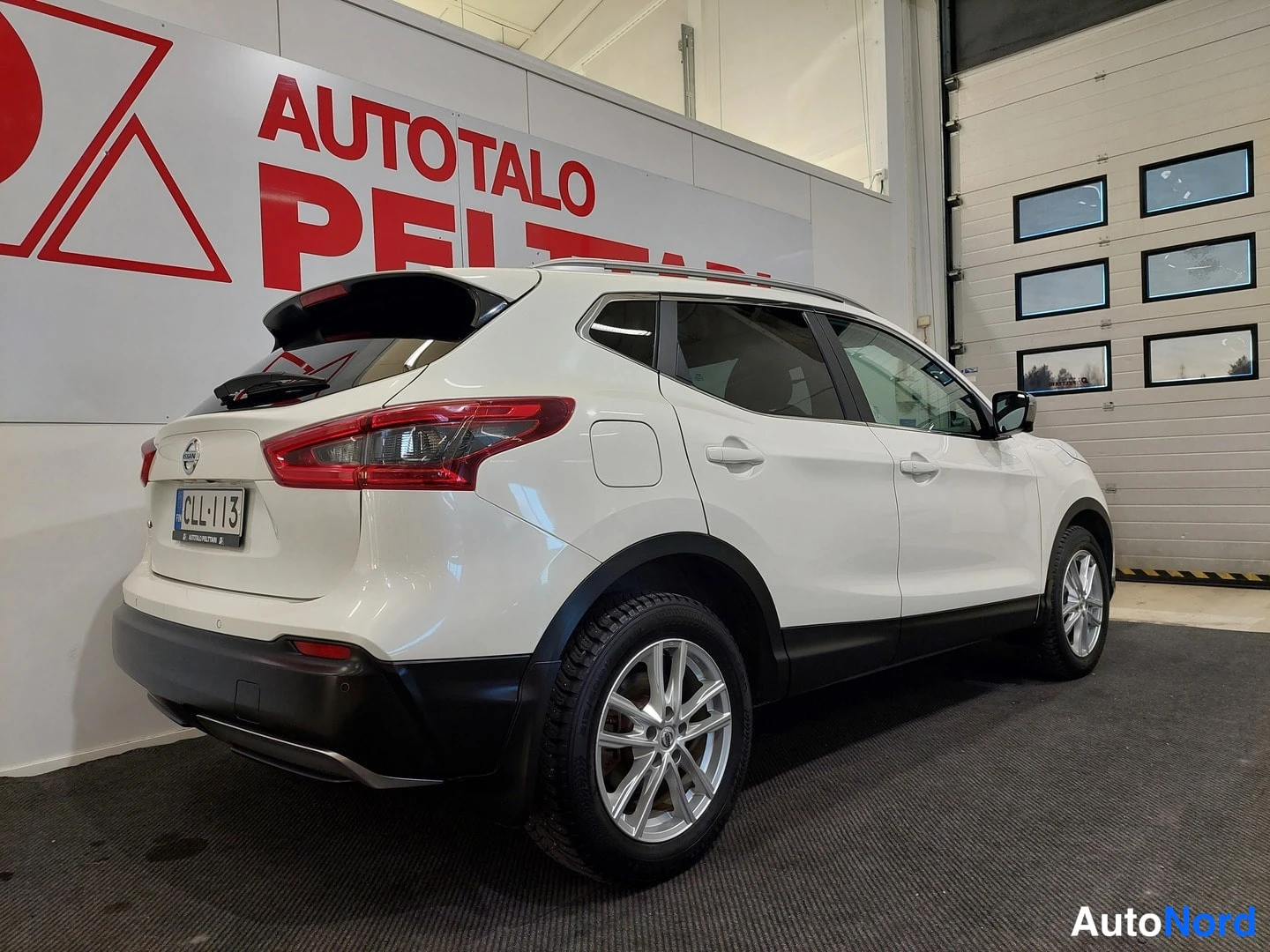 Takaviisto: Valkoinen Nissan Qashqai takakulmasta, rekisterikilpi, perä vasemmalla.