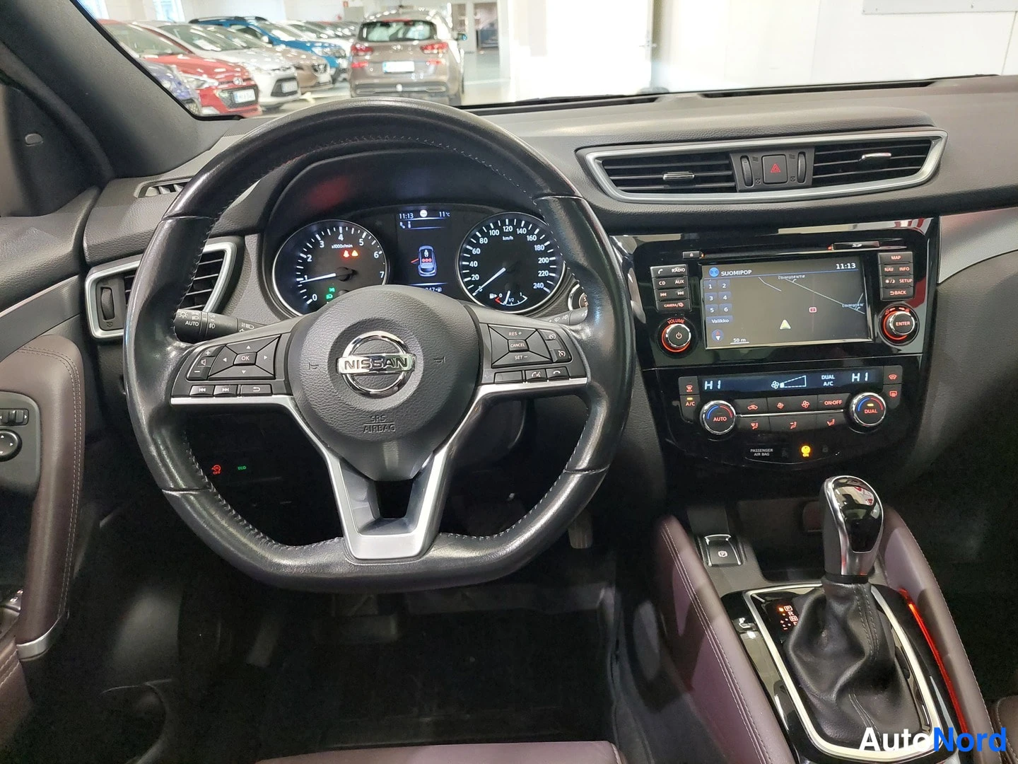 Muu: Nissan Qashqaiin ohjaamon kojelauta ja ohjauspyörä sisätiloissa, mittaristo ja kosketusnäyttö näkyvissä.