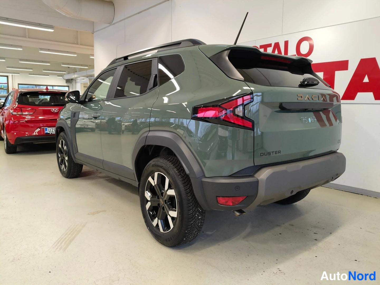 Takaviisto: Vihreä Dacia Duster -porrasperä näkyvät takaa ja oikealta sivulta autotalloon sisätiloissa; takavaloja, Dacia-merkintä ja Duster-tunnus näkyvät.
