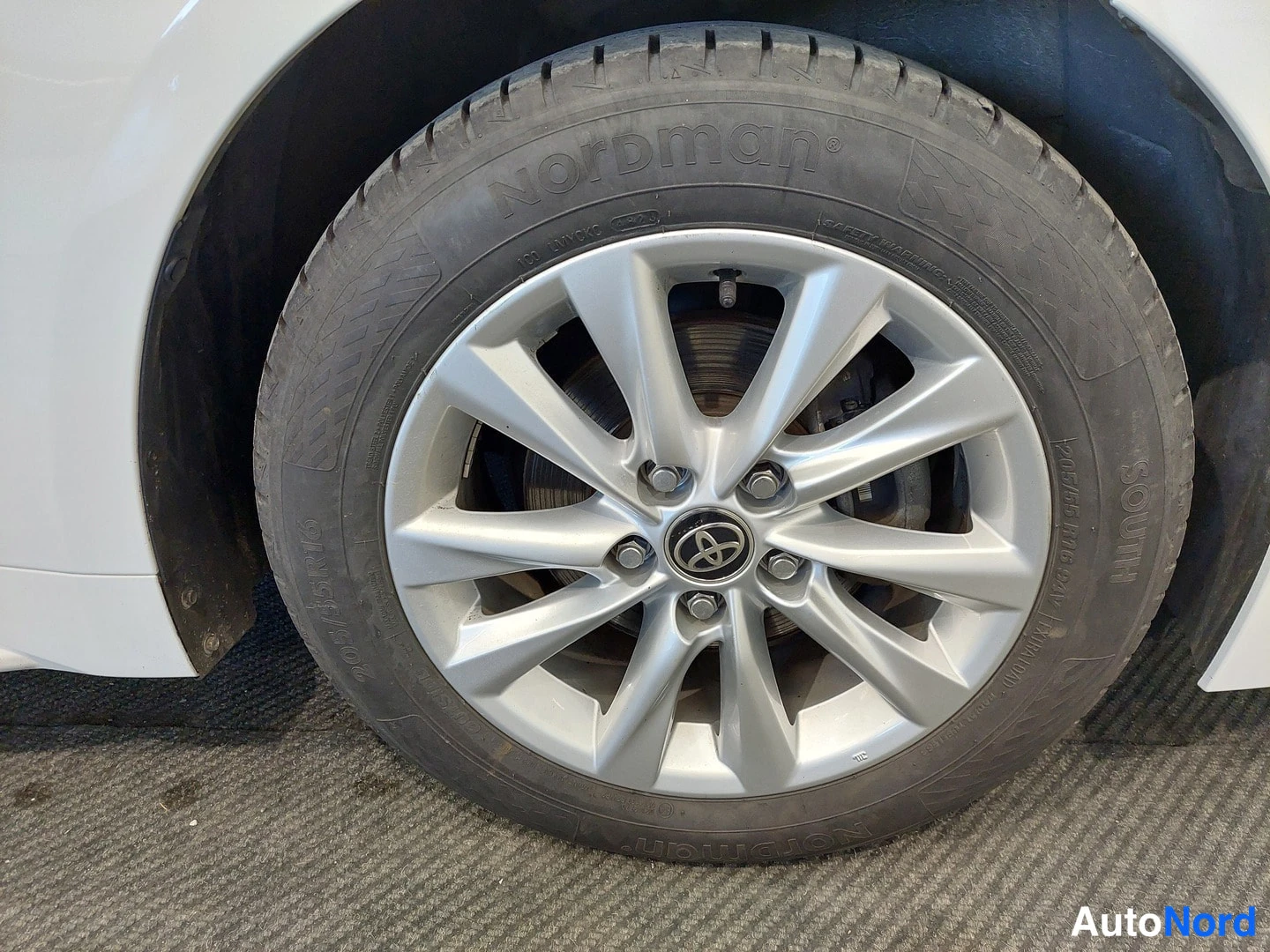 Muu: Valkoisen auton etupyörän hopeavanteella ja Nordman-tyres-renkaalla.
